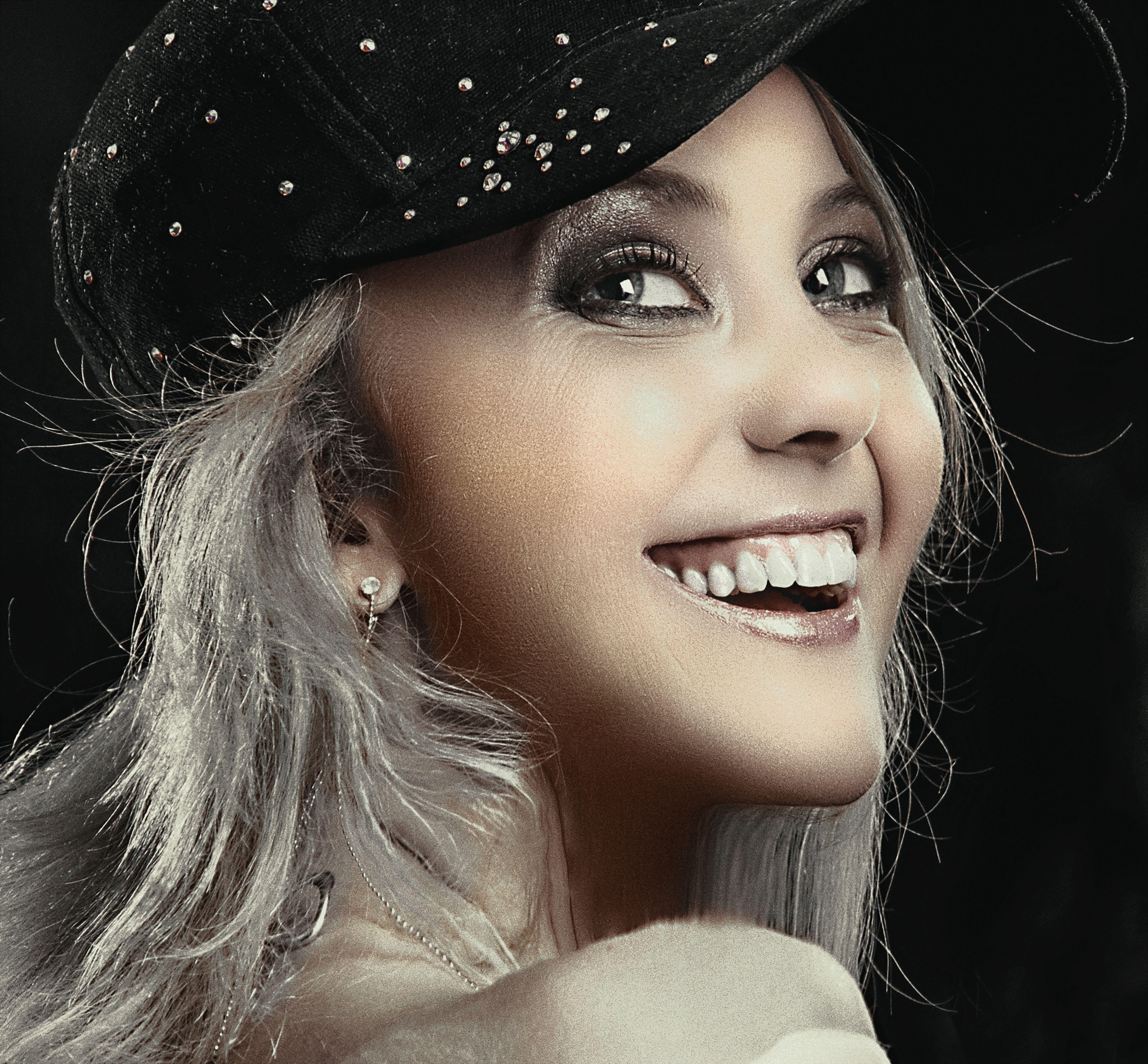 Charming portrait of a woman wearing a decorated hat, showcasing elegance and joy.