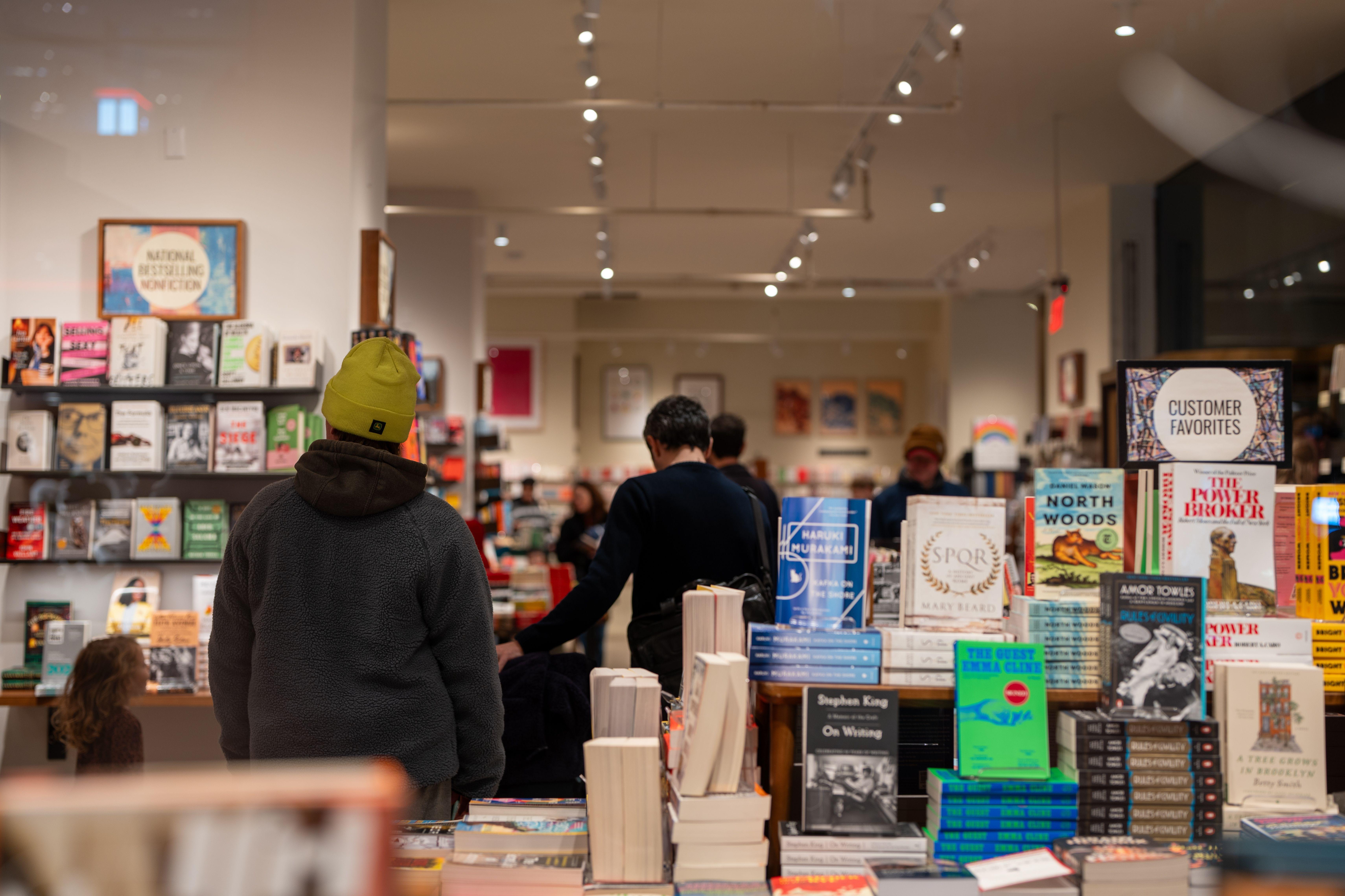 Warmly lit bookstore in New York City with people browsing through bookshelves.