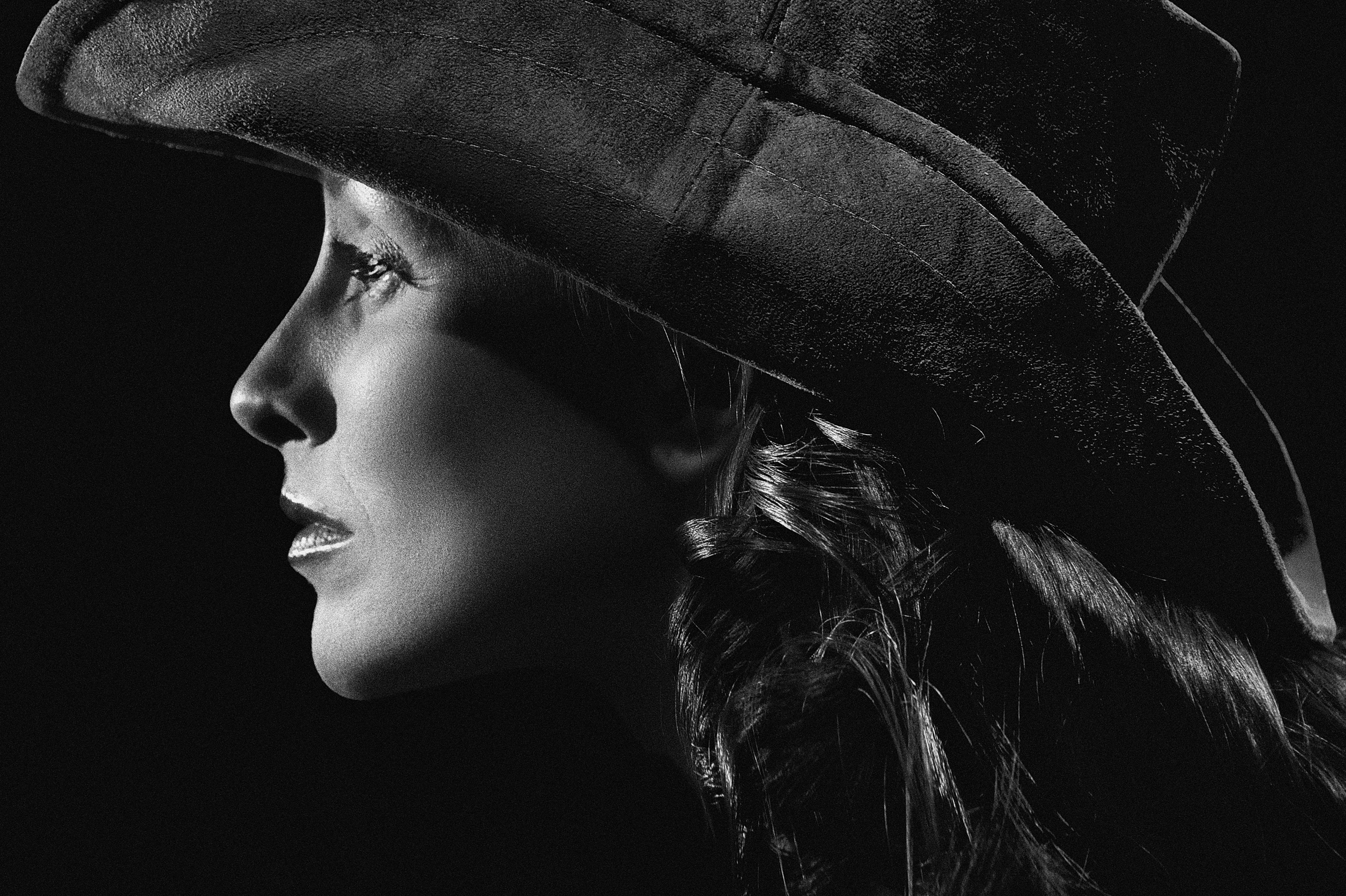 Elegant black and white side profile portrait of a woman wearing a hat.