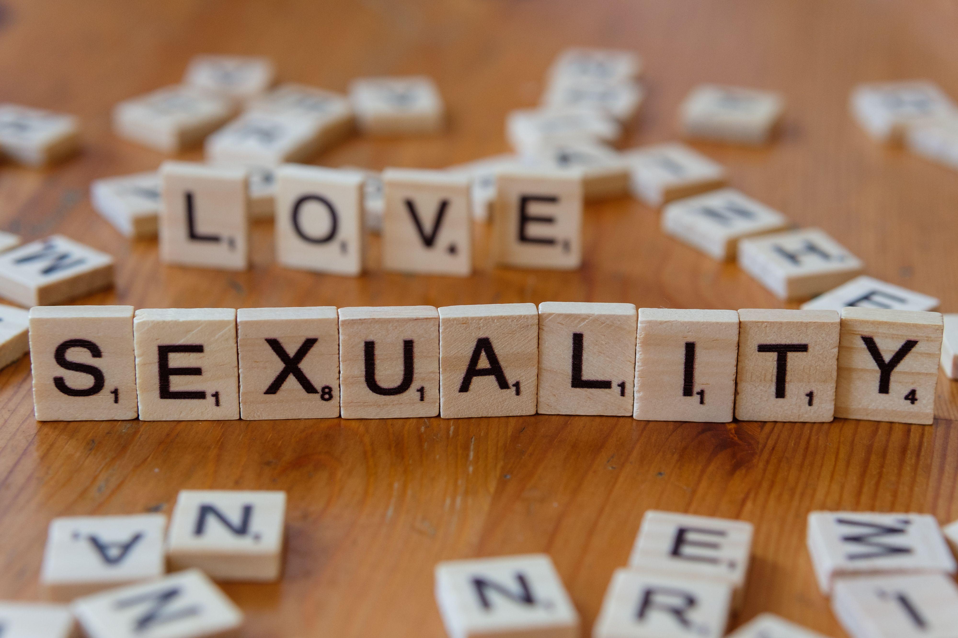 Wooden letter tiles spelling 'Love' and 'Sexuality' on a wooden table.