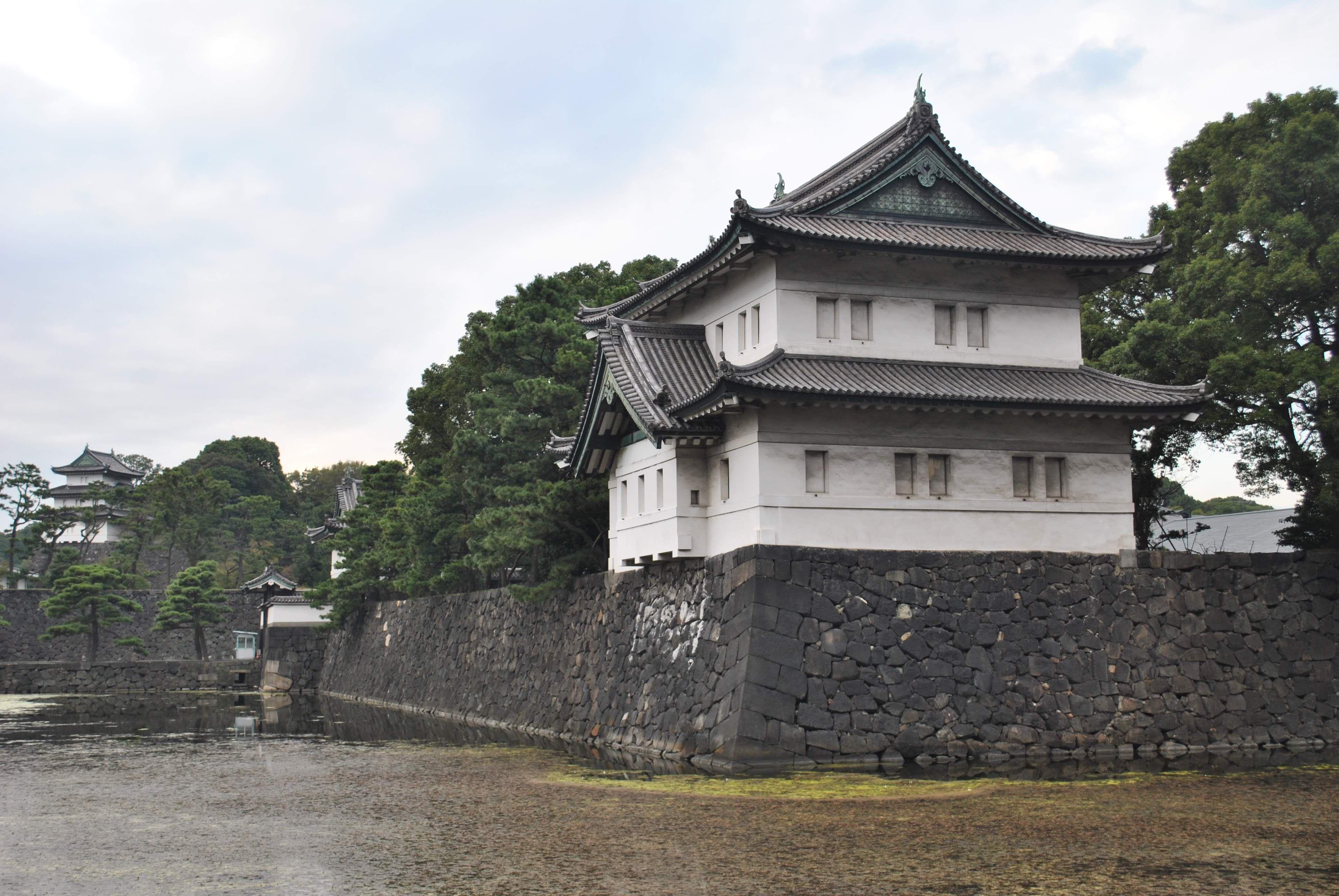 Serene exterior of Tokyo's Imperial Palace surrounded by lush greenery and stone walls.