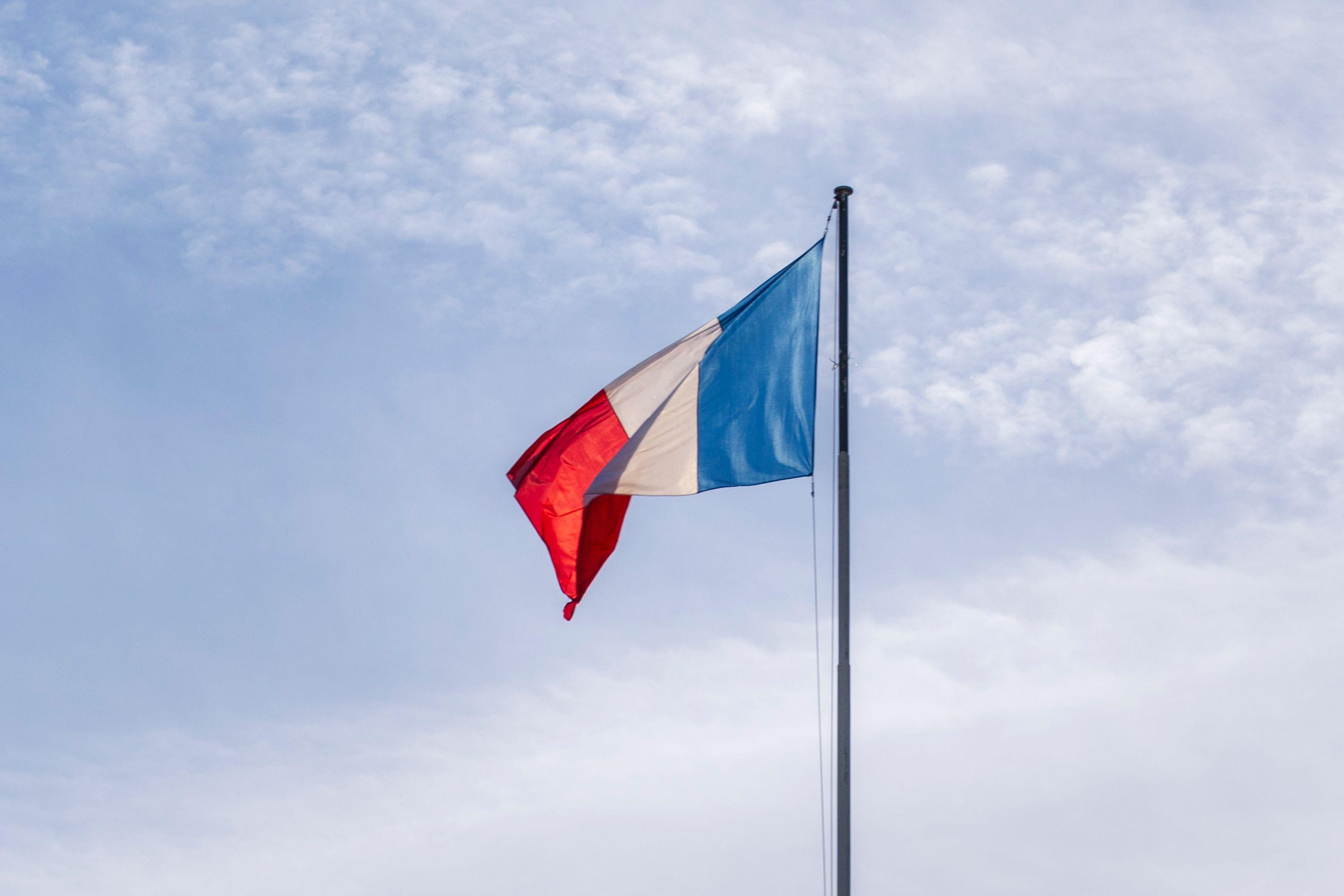 The French national flag waving against a blue sky in Paris, France.