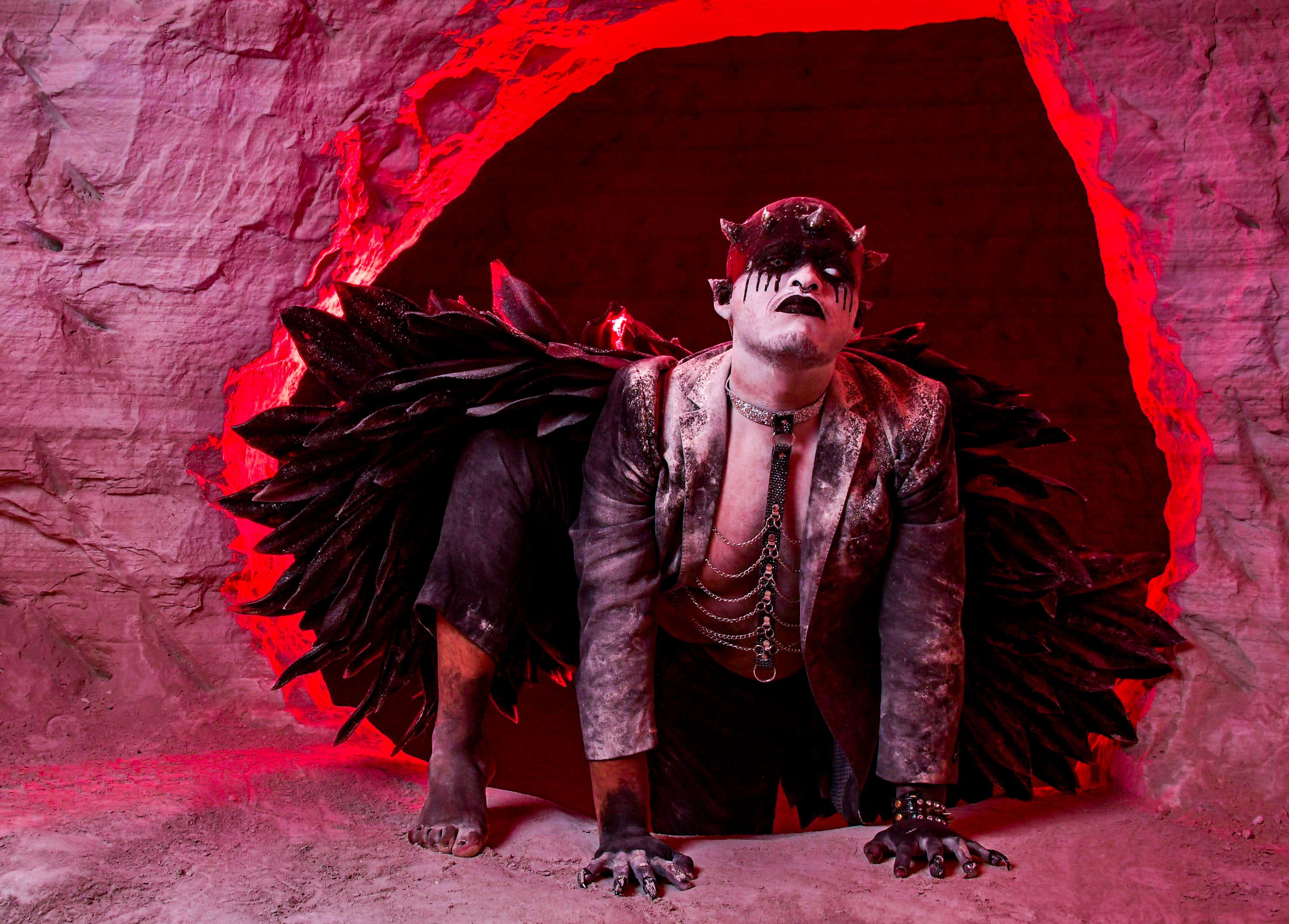 A fantasy character in dark costume emerges from a red-lit cave, creating a dramatic and surreal atmosphere.