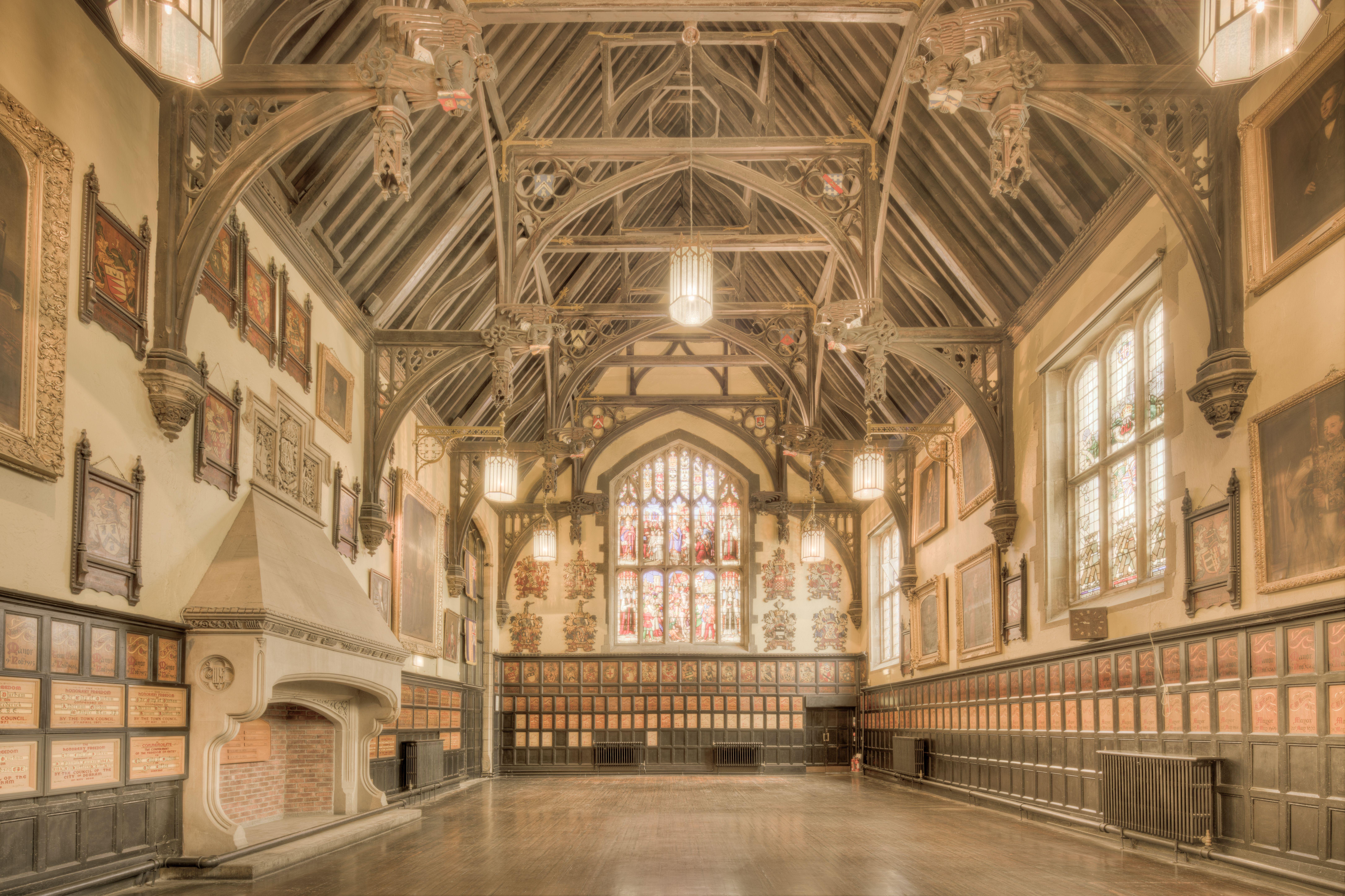 A beautiful historic hall in England featuring ornate timber architecture and stained glass windows.