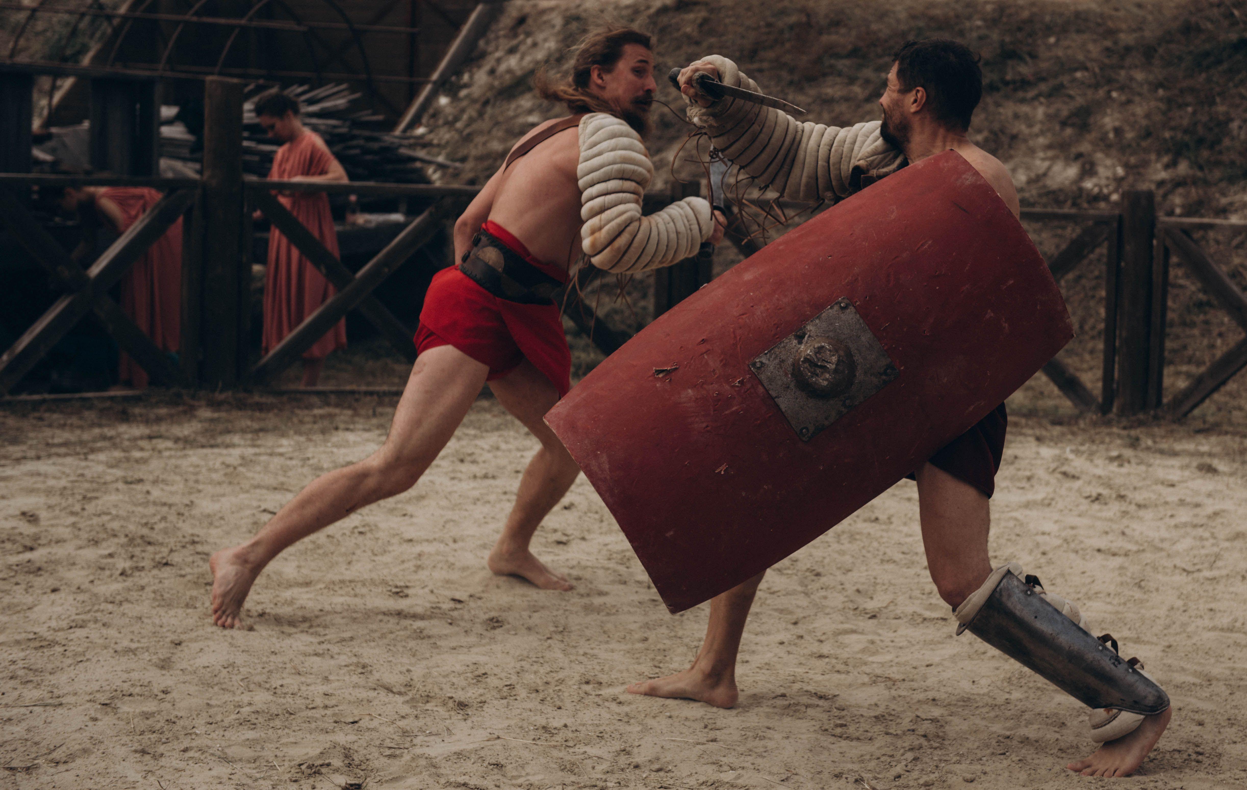 Two gladiators engaged in intense combat in a historical arena setting.