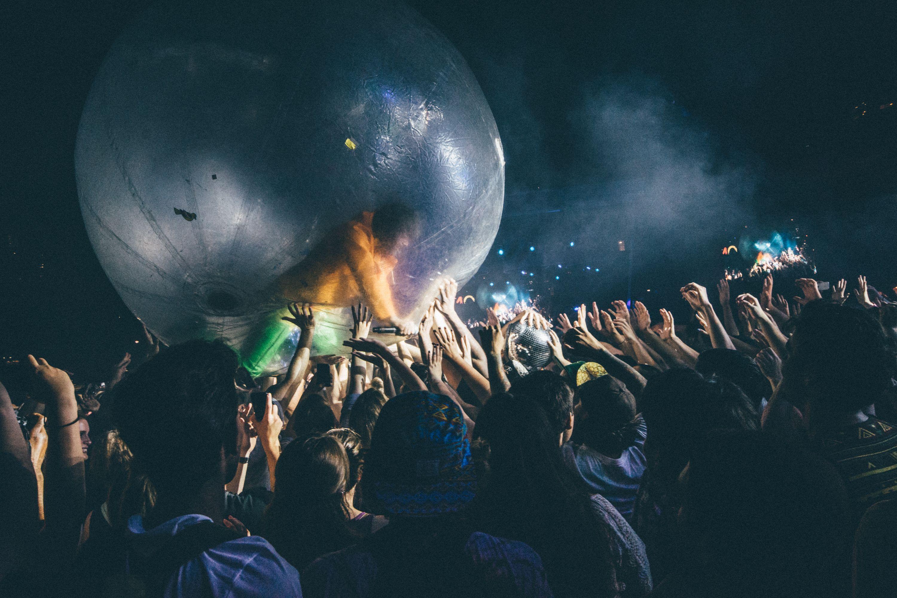 A lively night concert with people interacting with a large zorb ball.