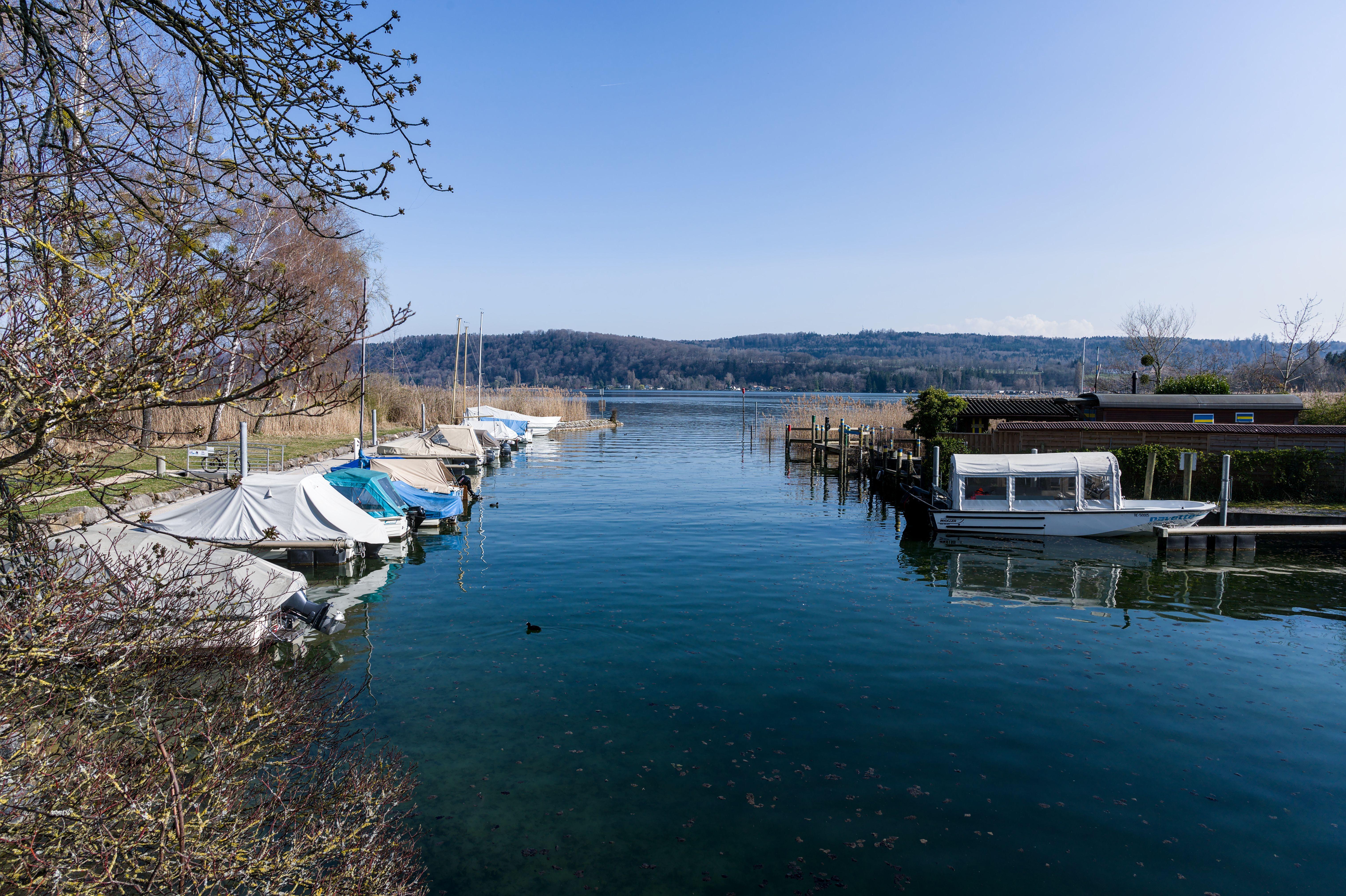 Peaceful Swiss lake scene with docked boats and clear blue sky in springtime