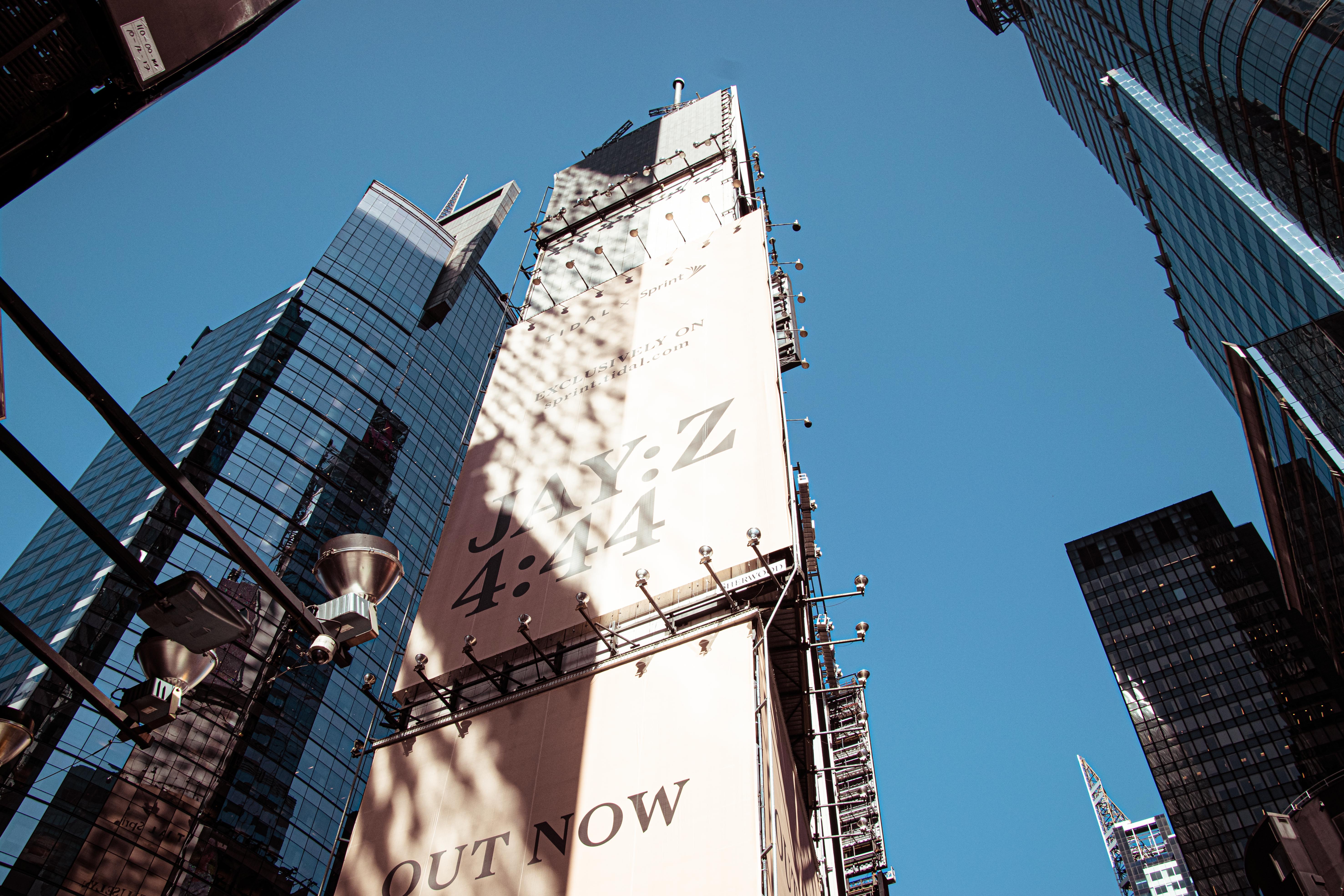 Low angle view of skyscrapers and advertisement in New York City, showcasing urban architecture.