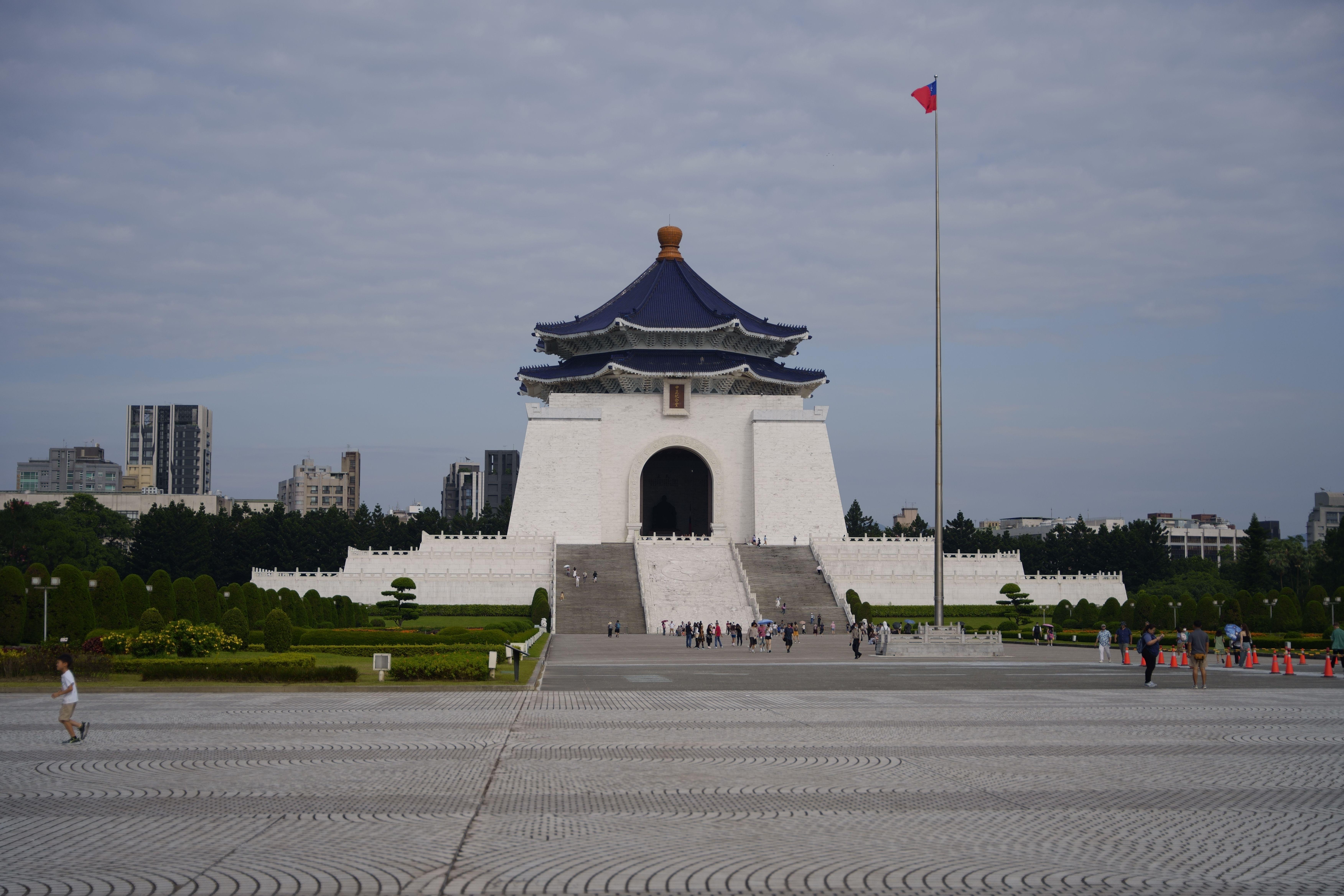 Chiang Kai-shek Memorial Hall with Taiwanese flag in Taipei. Iconic landmark with visitors.