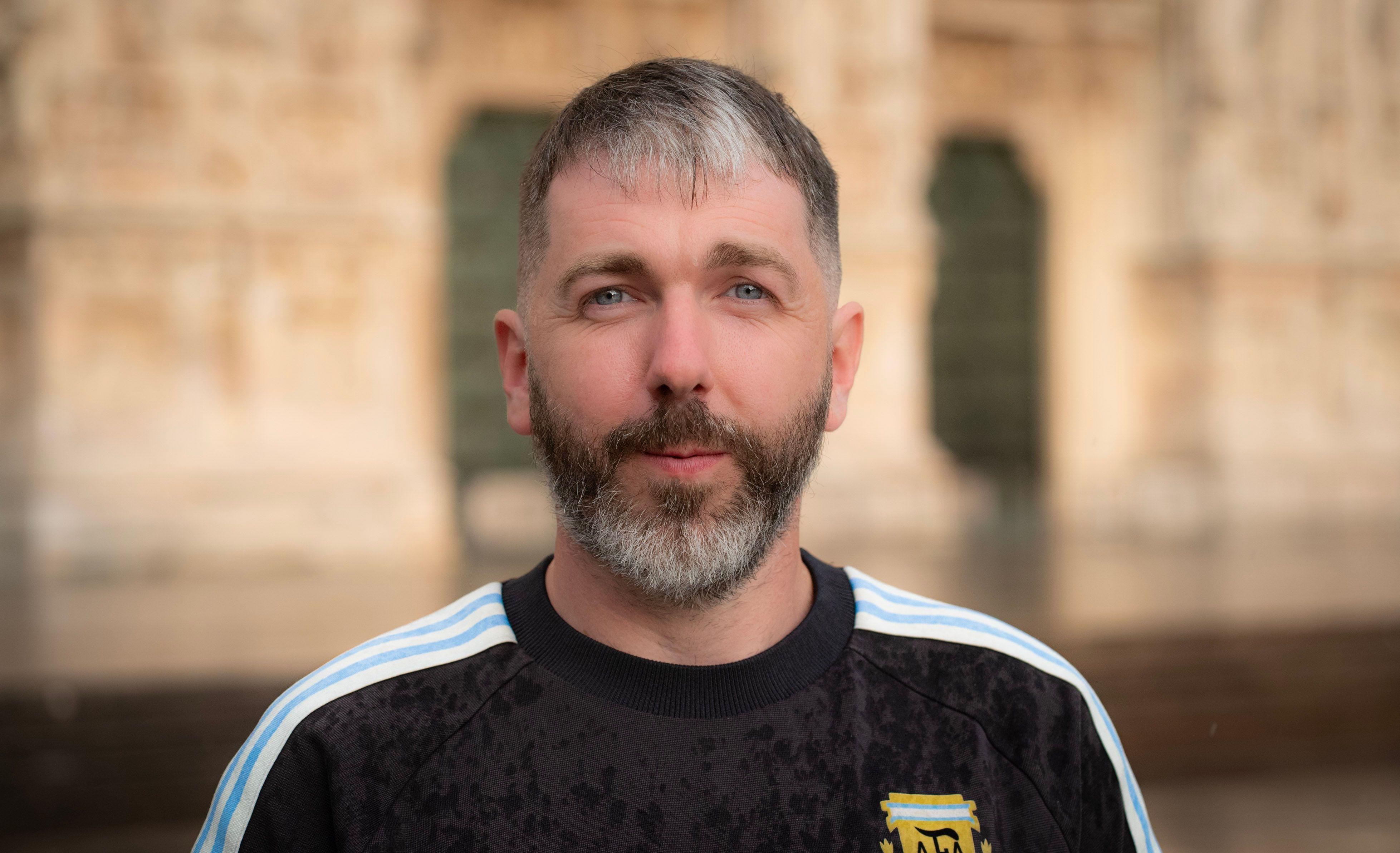 Close-up portrait of a man in Milan with historic architecture in the background.