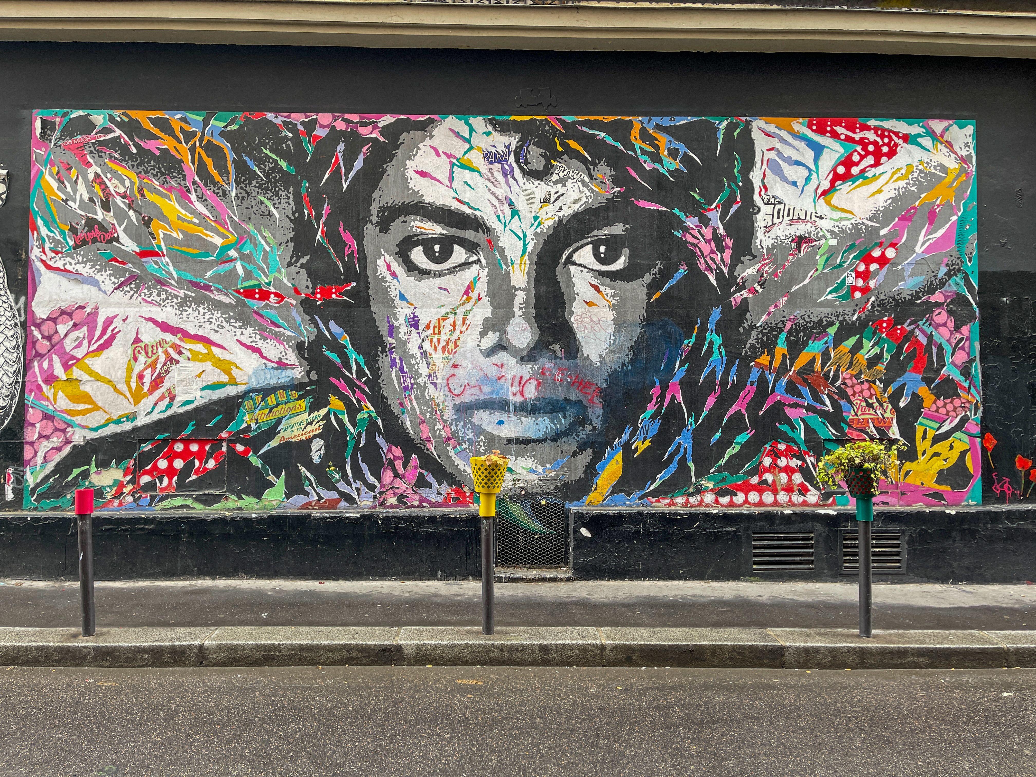 Vibrant mural of a face painted on a wall in Montmartre, Paris, showcasing dynamic street art style.