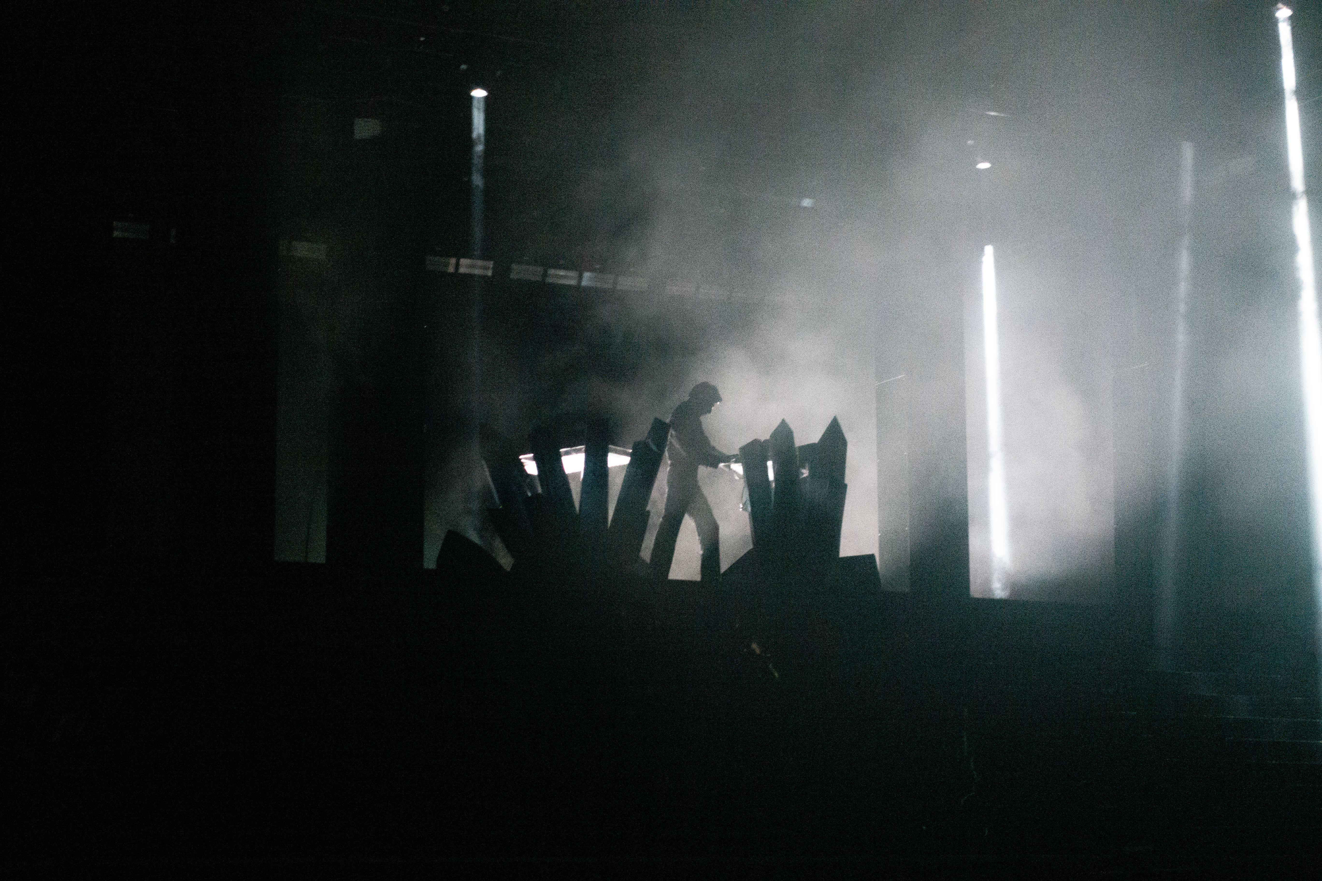 Silhouette of a performer on stage amidst intense lighting and smoke effects.