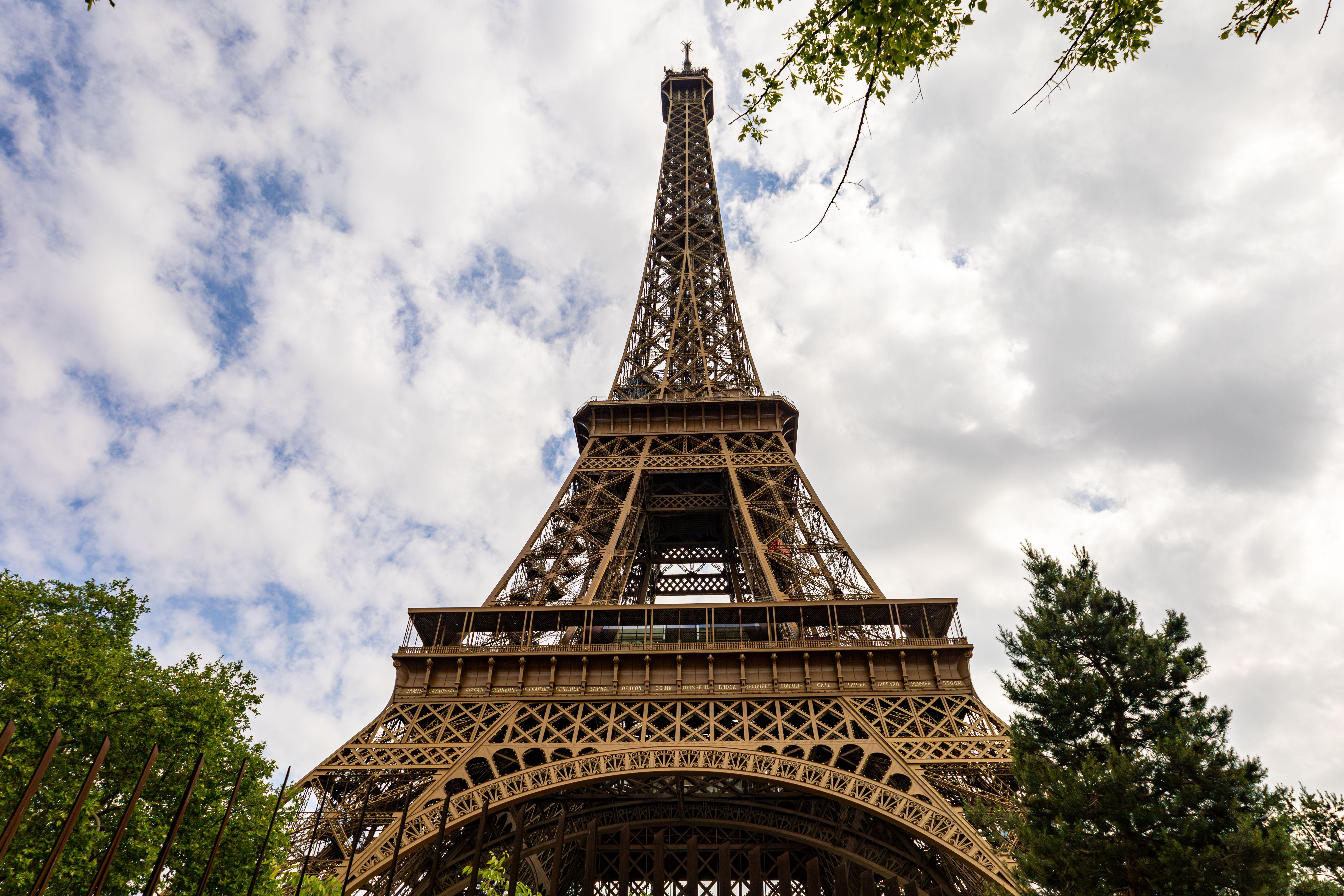 A captivating upward view of the Eiffel Tower against a cloudy sky in Paris.