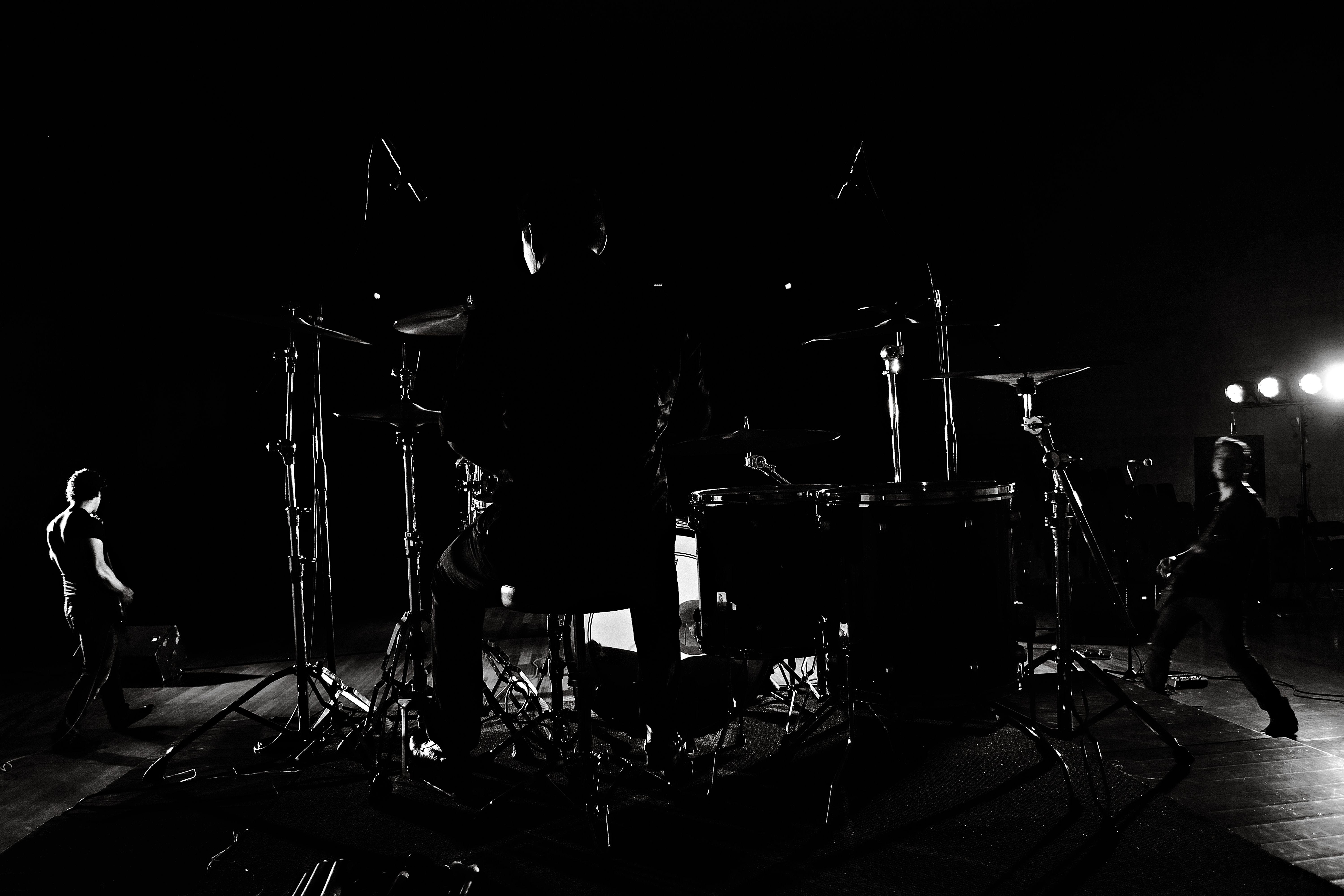 Dramatic black and white backstage view of a band performing live on stage.