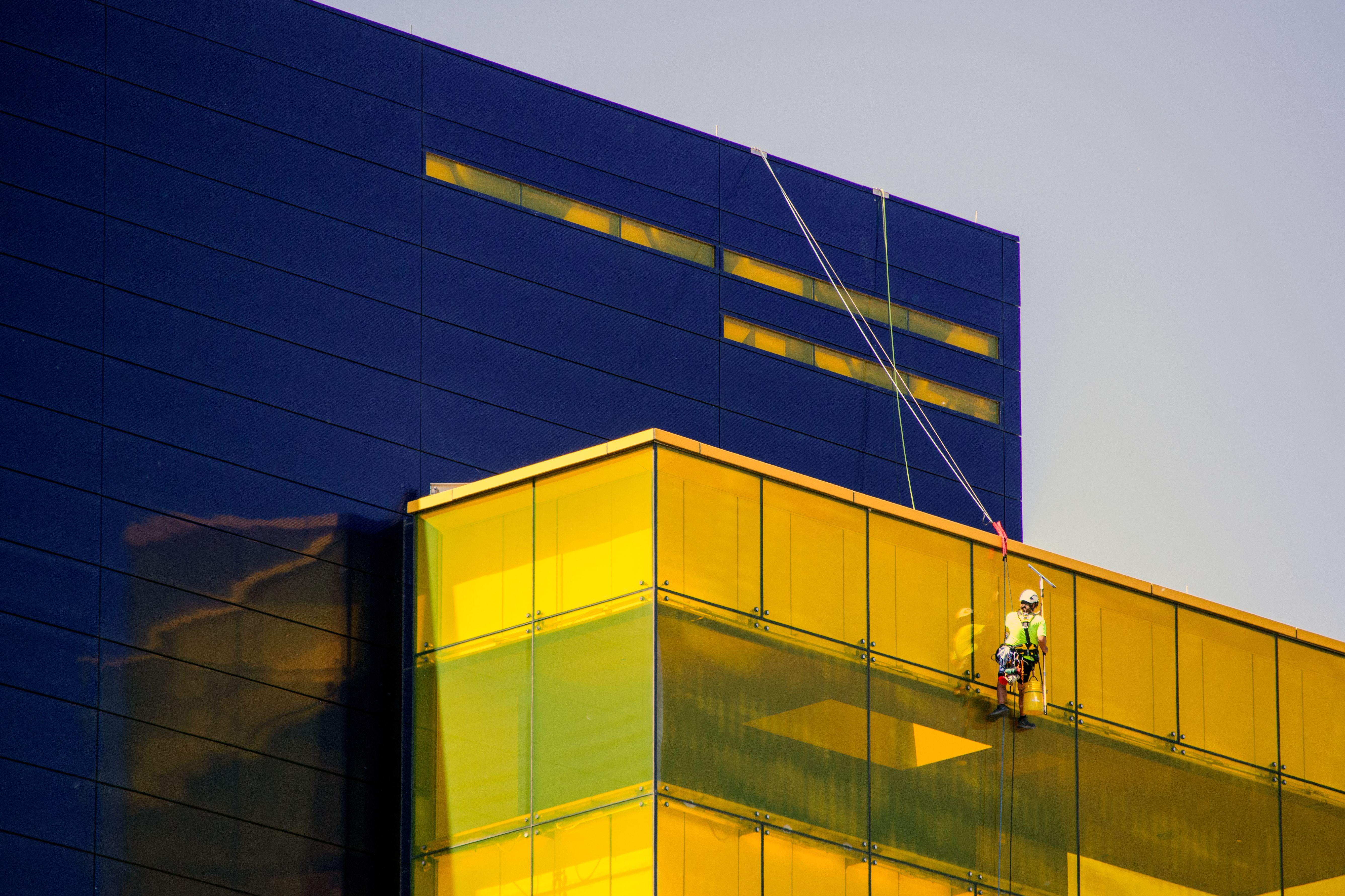 Professional window cleaner at Guthrie Theater in Minneapolis using safety harness.