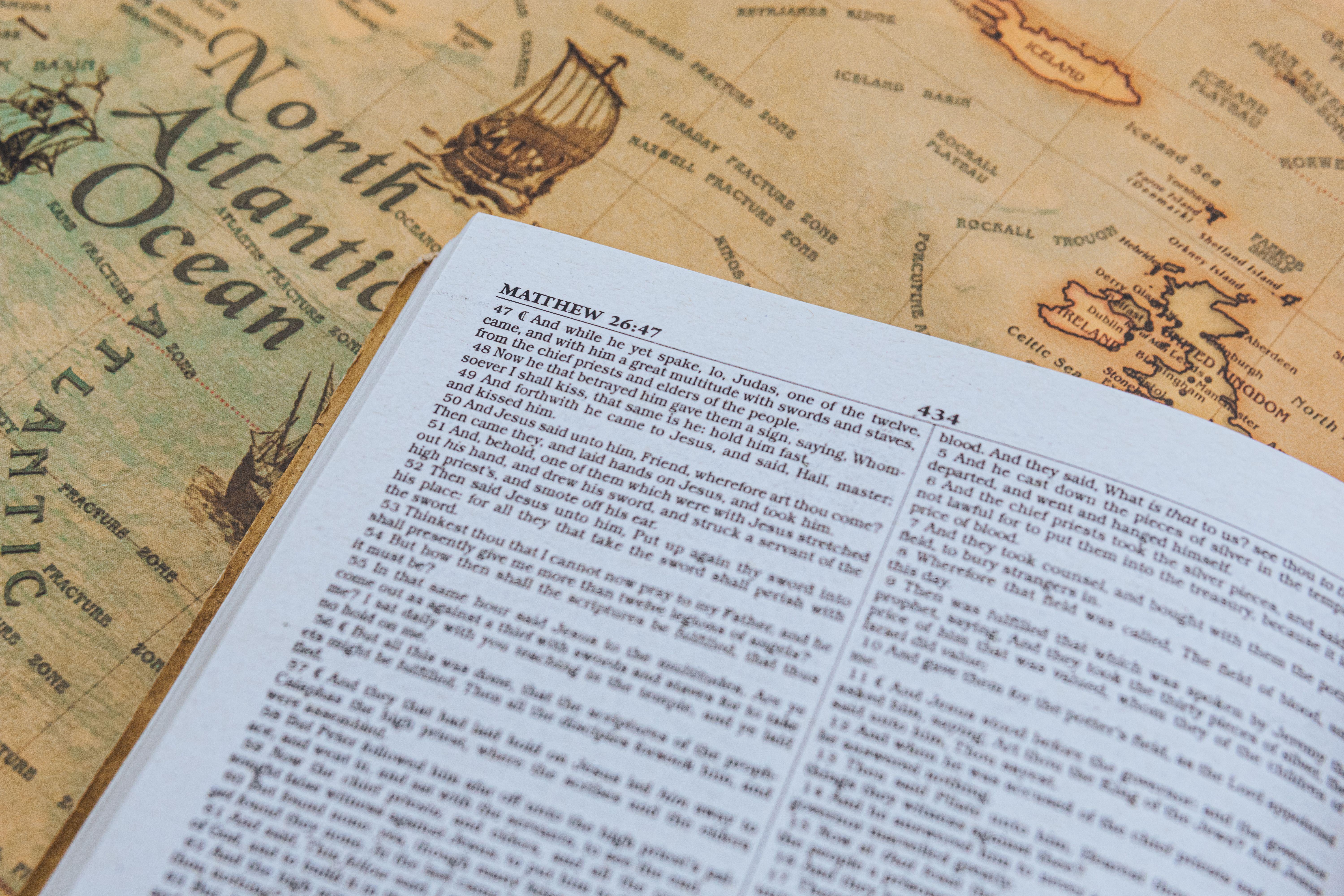 Open Bible with text from Matthew 26:47 on vintage map of North Atlantic Ocean.