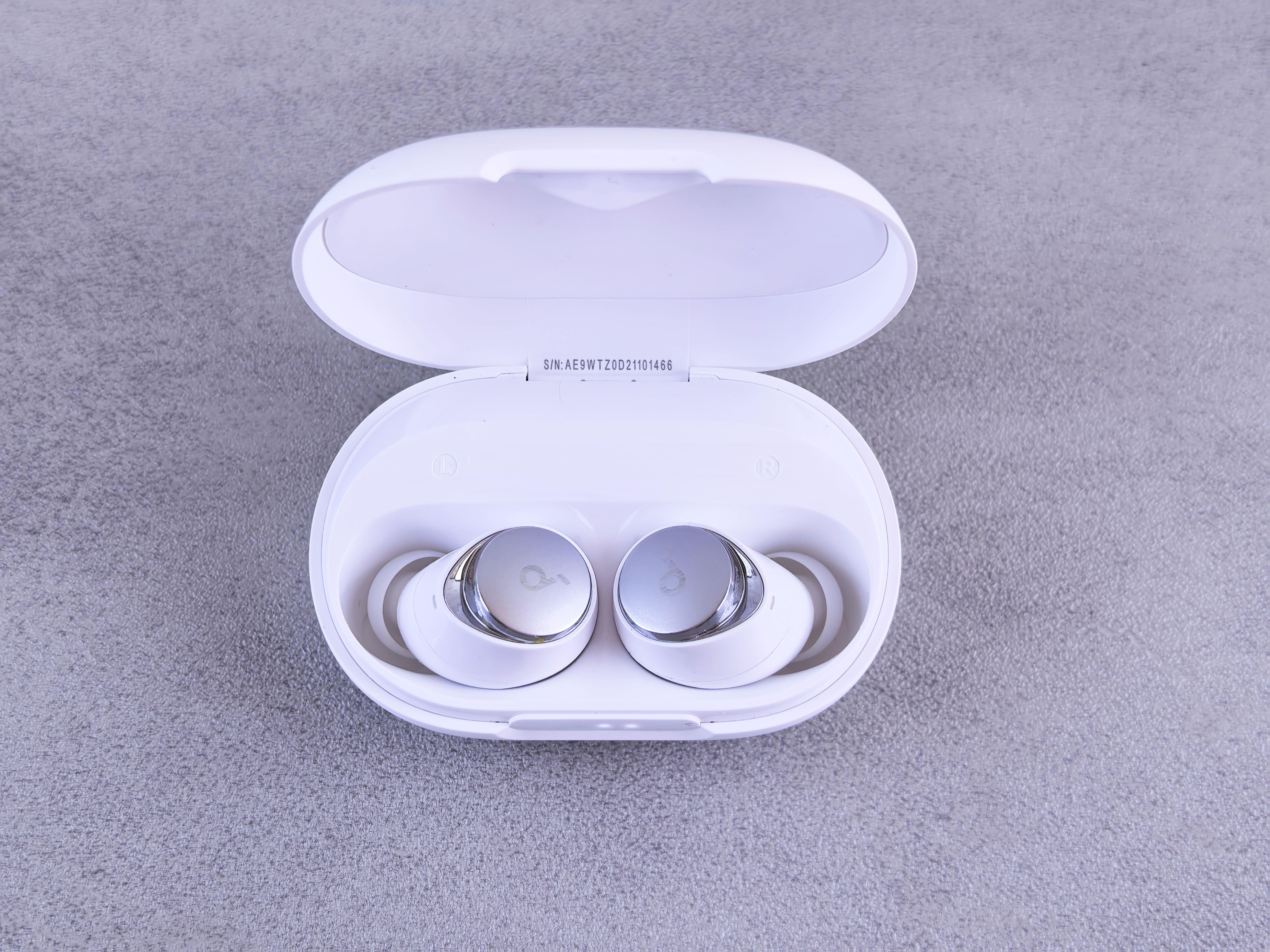 High-quality white wireless earbuds displayed in an open charging case on a textured surface.