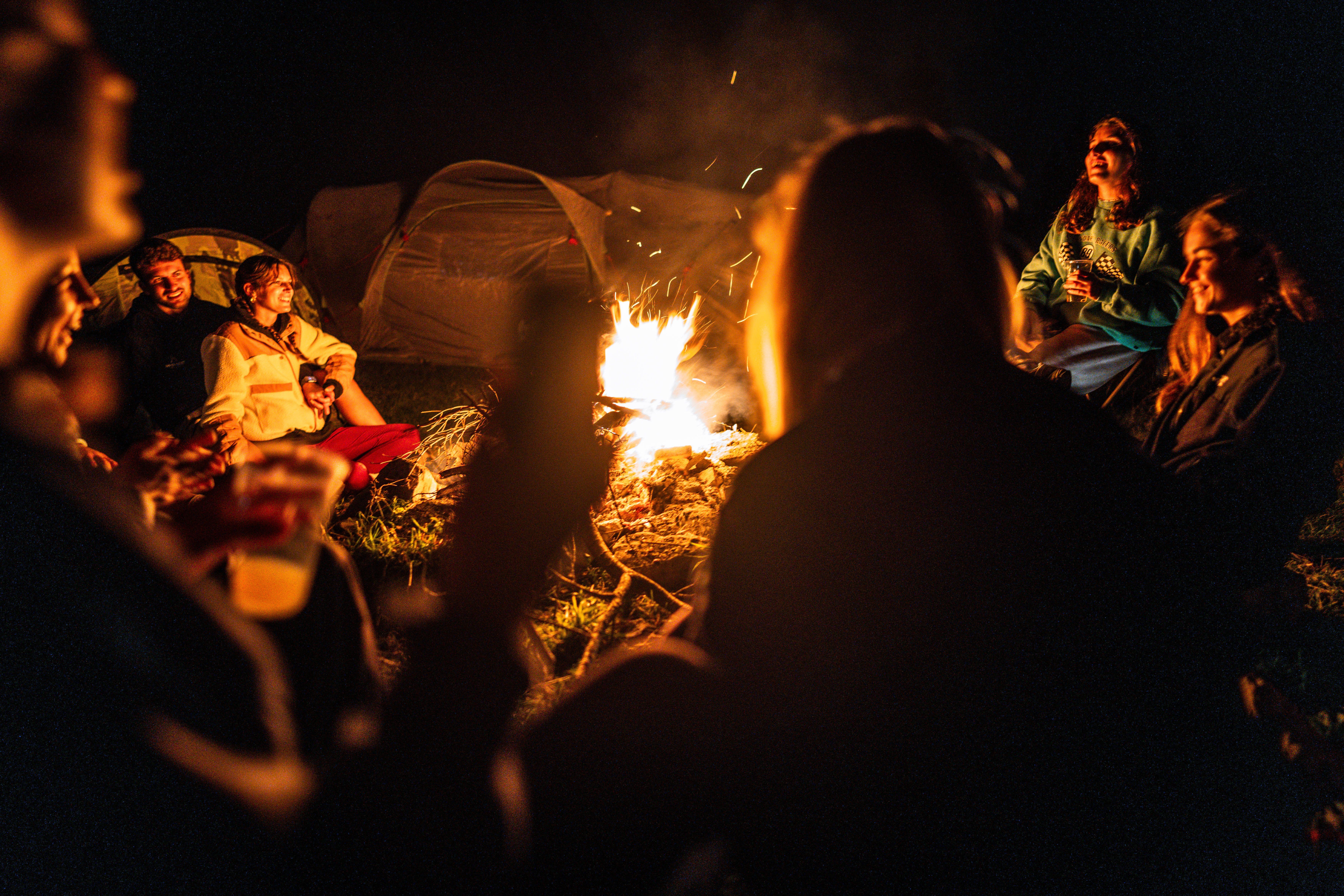 A cozy group campfire scene with friends enjoying a night outdoors in Schilpario, Lombardia, Italy.