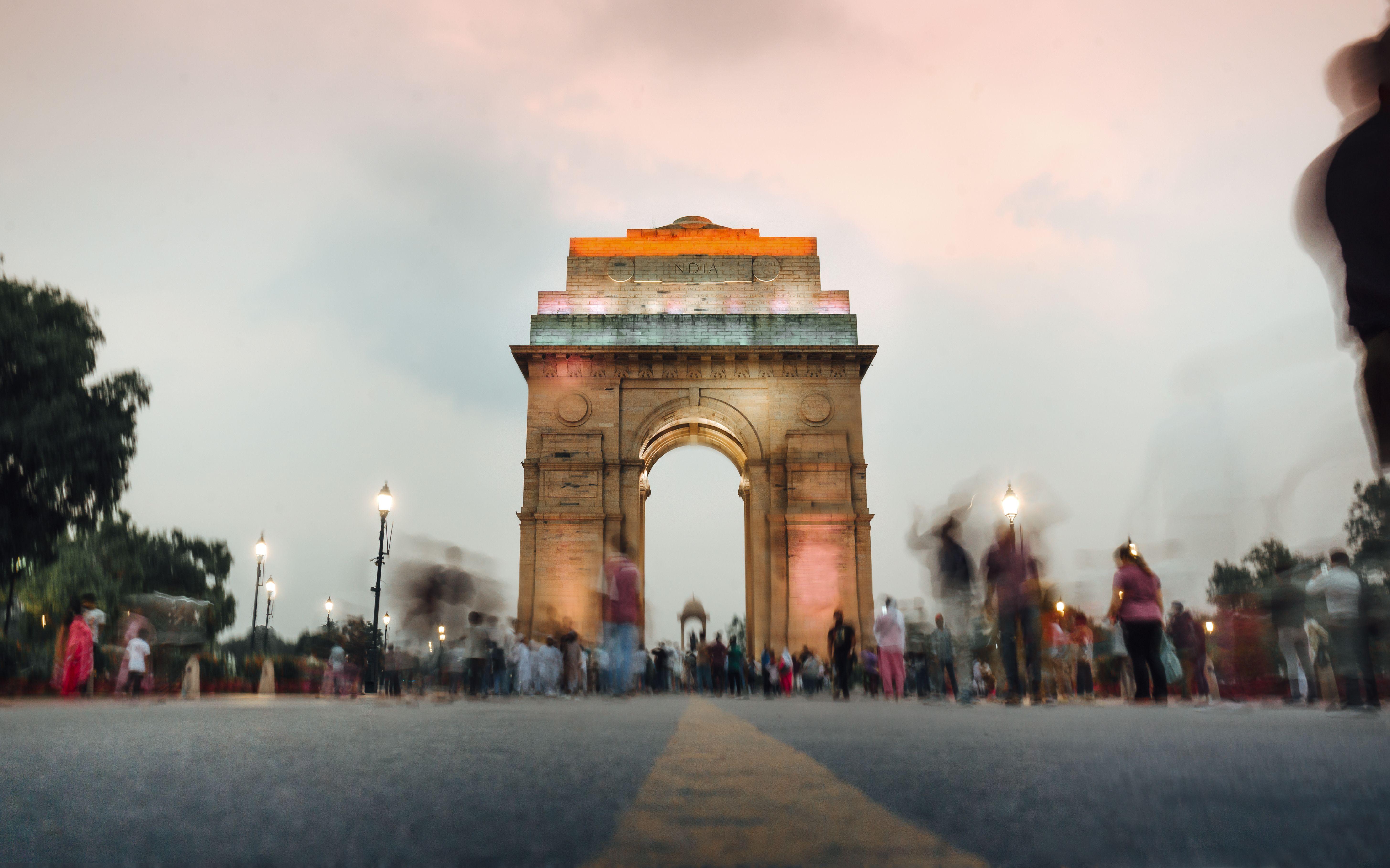 A stunning view of India Gate in New Delhi at sunset with a dynamic crowd.