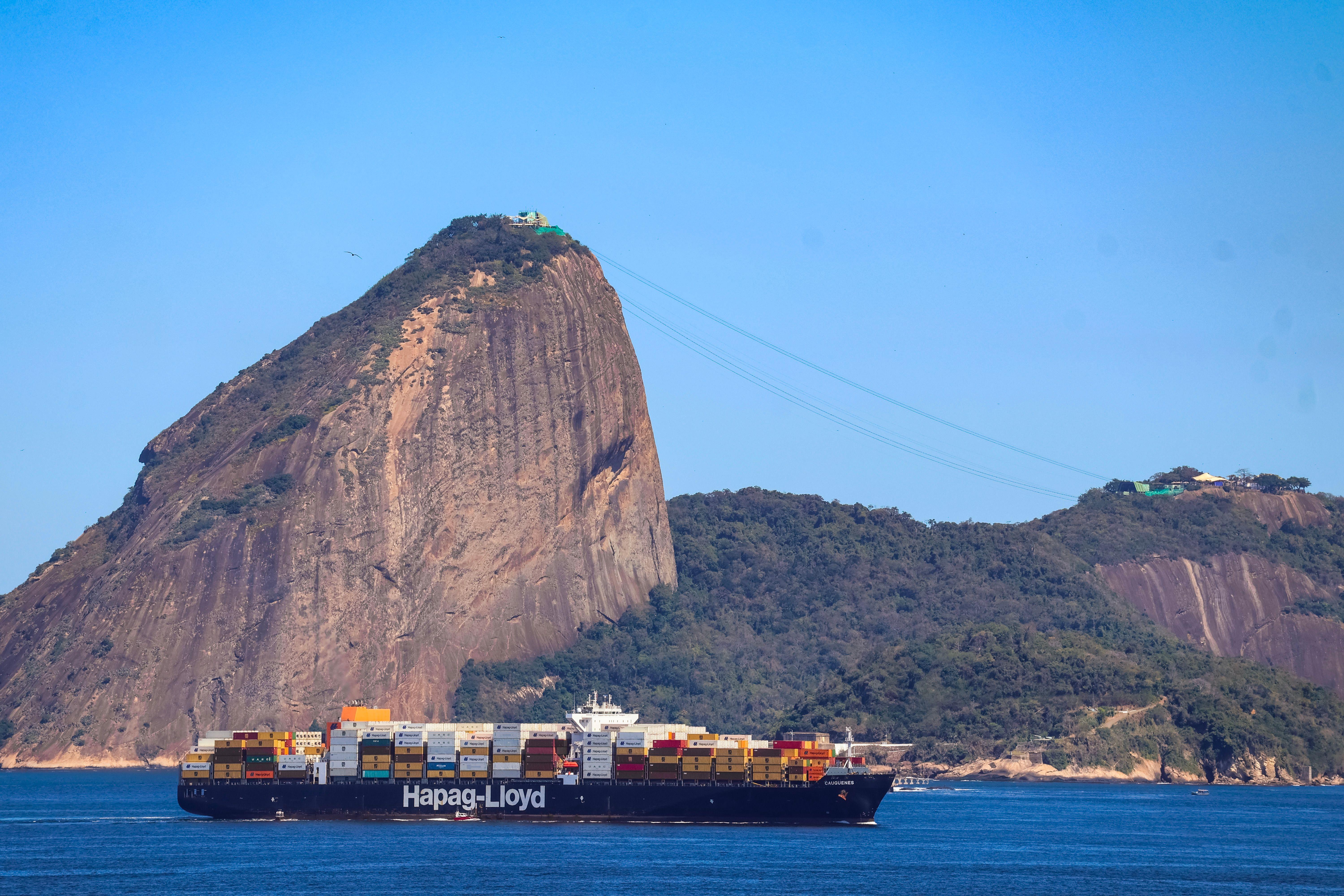 Container ship passing by Sugarloaf Mountain in Rio de Janeiro on a clear day, showcasing global trade.