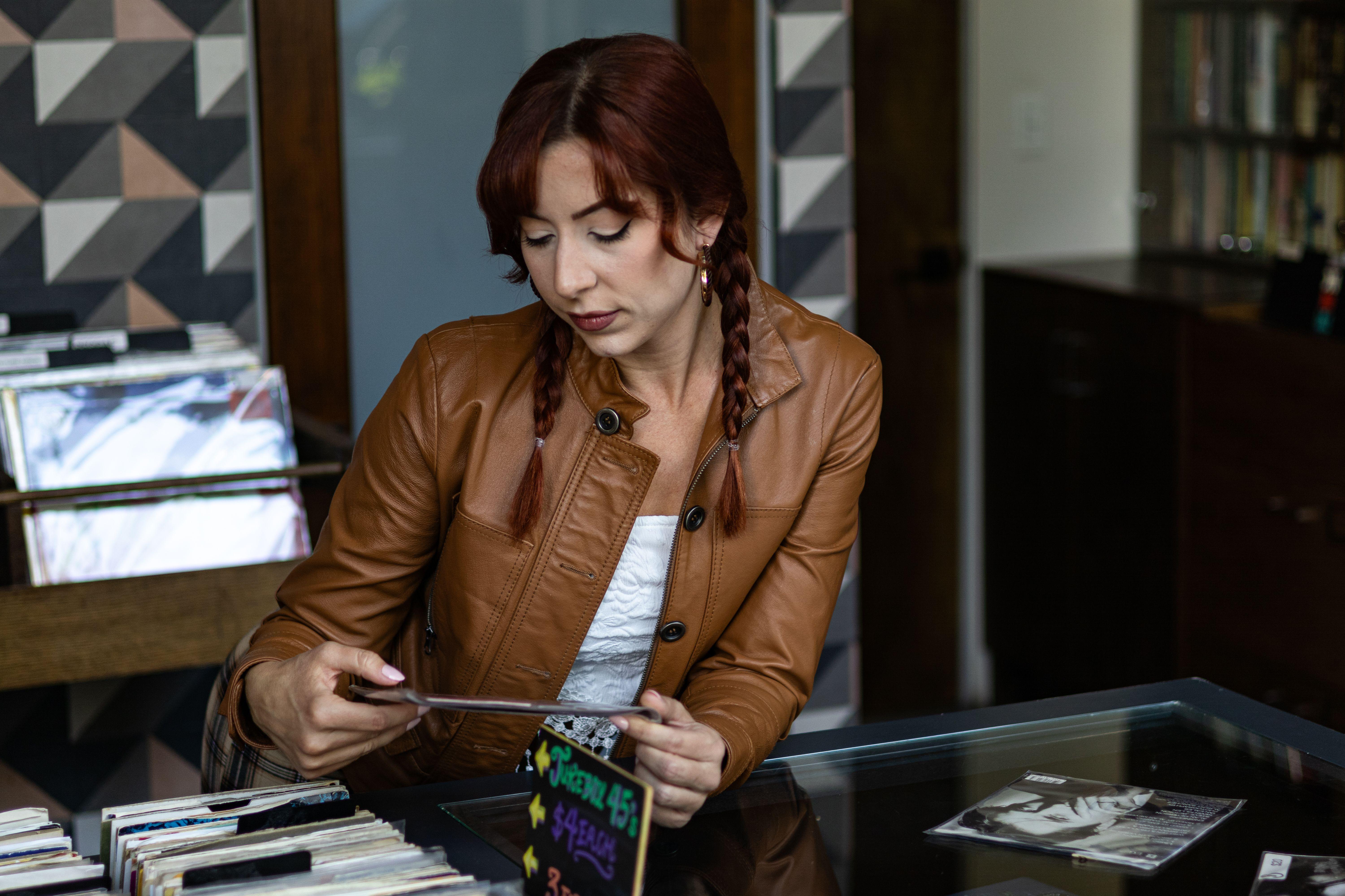 Woman in brown jacket searching through vinyl records in a vintage store.