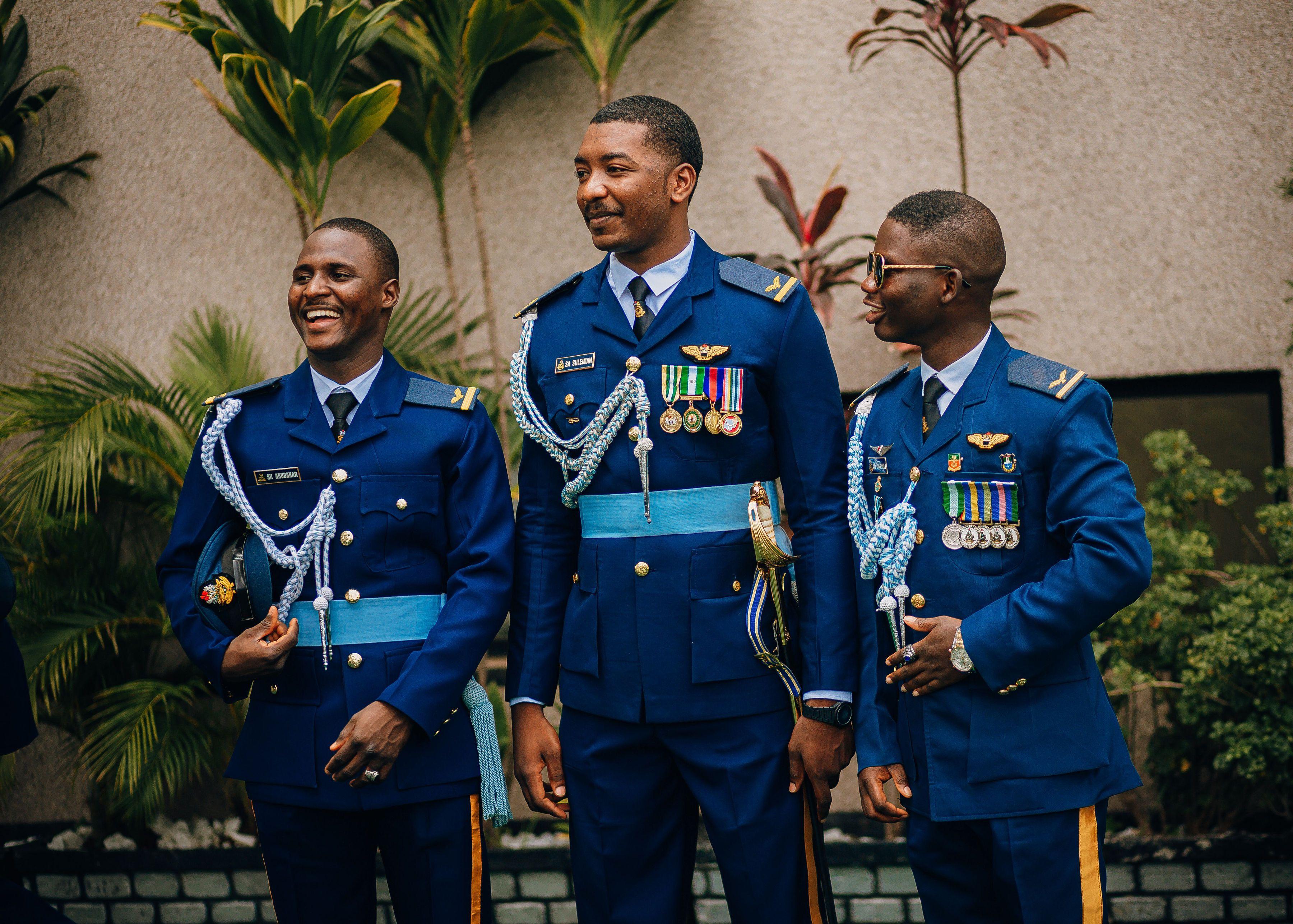 Three military officers in dress uniform adorned with medals, standing outdoors and smiling.