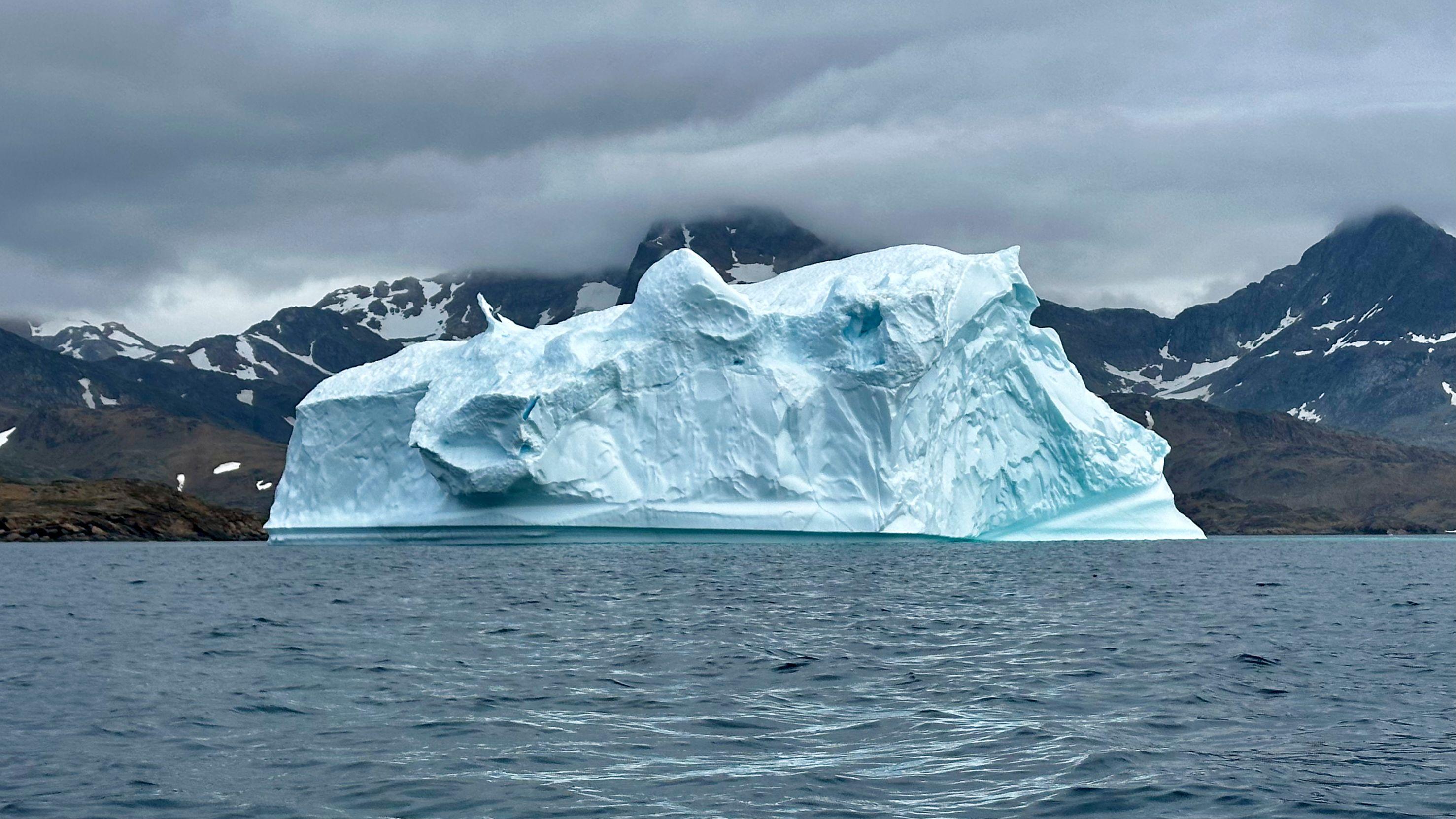 Expansive iceberg floating serenely in the cool waters of Greenland.