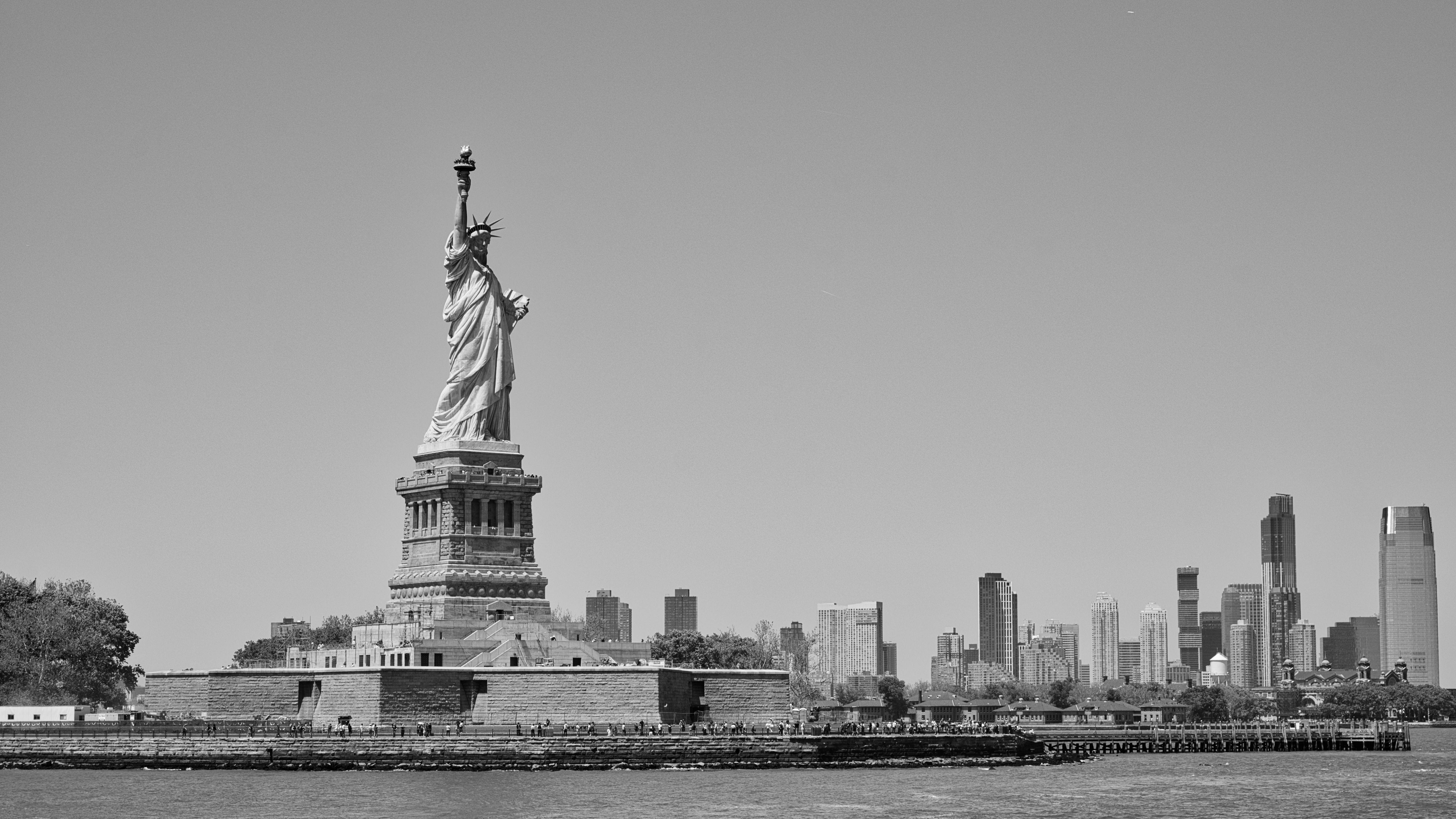 Black and white image of the Statue of Liberty with the New York City skyline.
