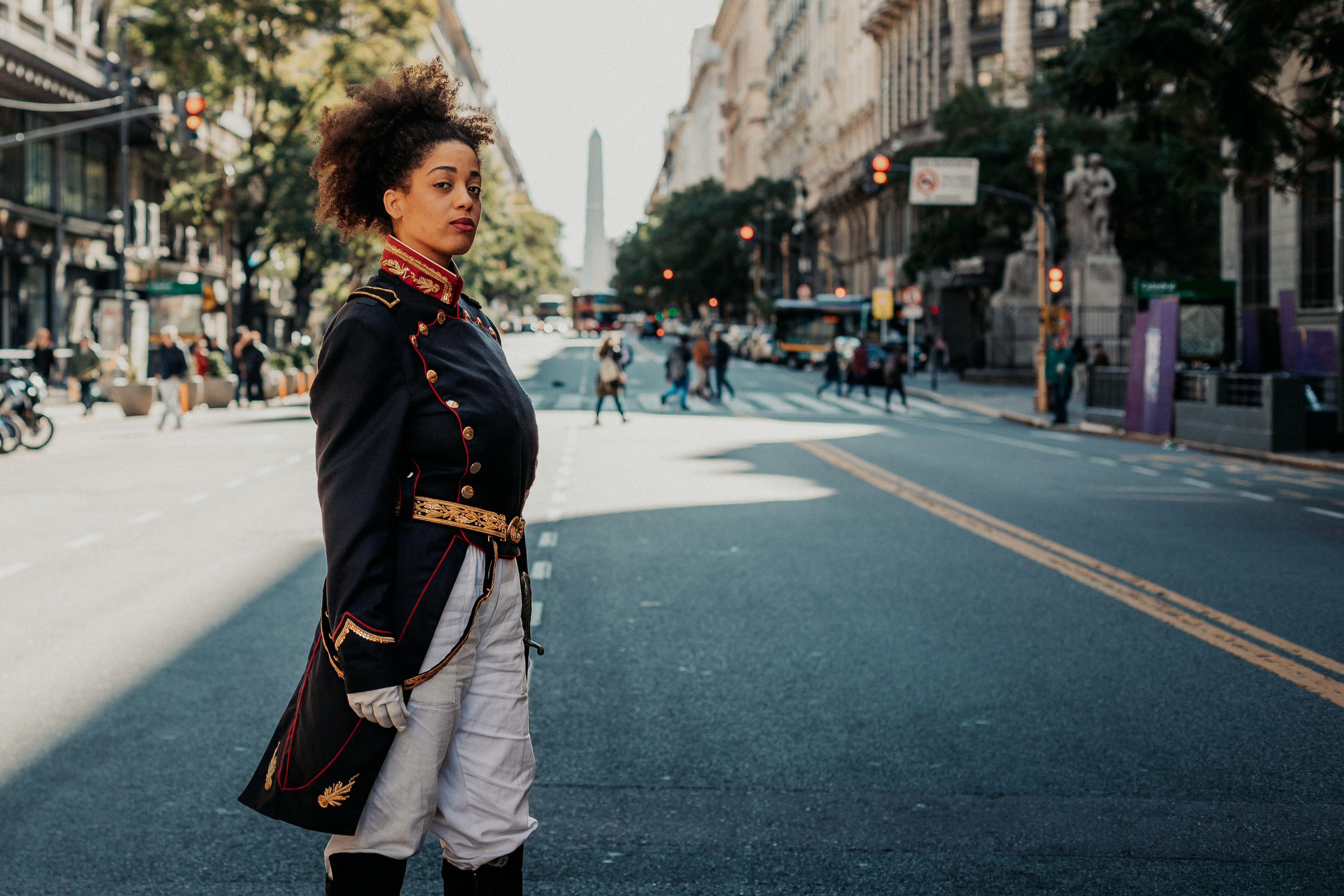 A woman in a historical military costume poses on a vibrant street in Buenos Aires, Argentina.