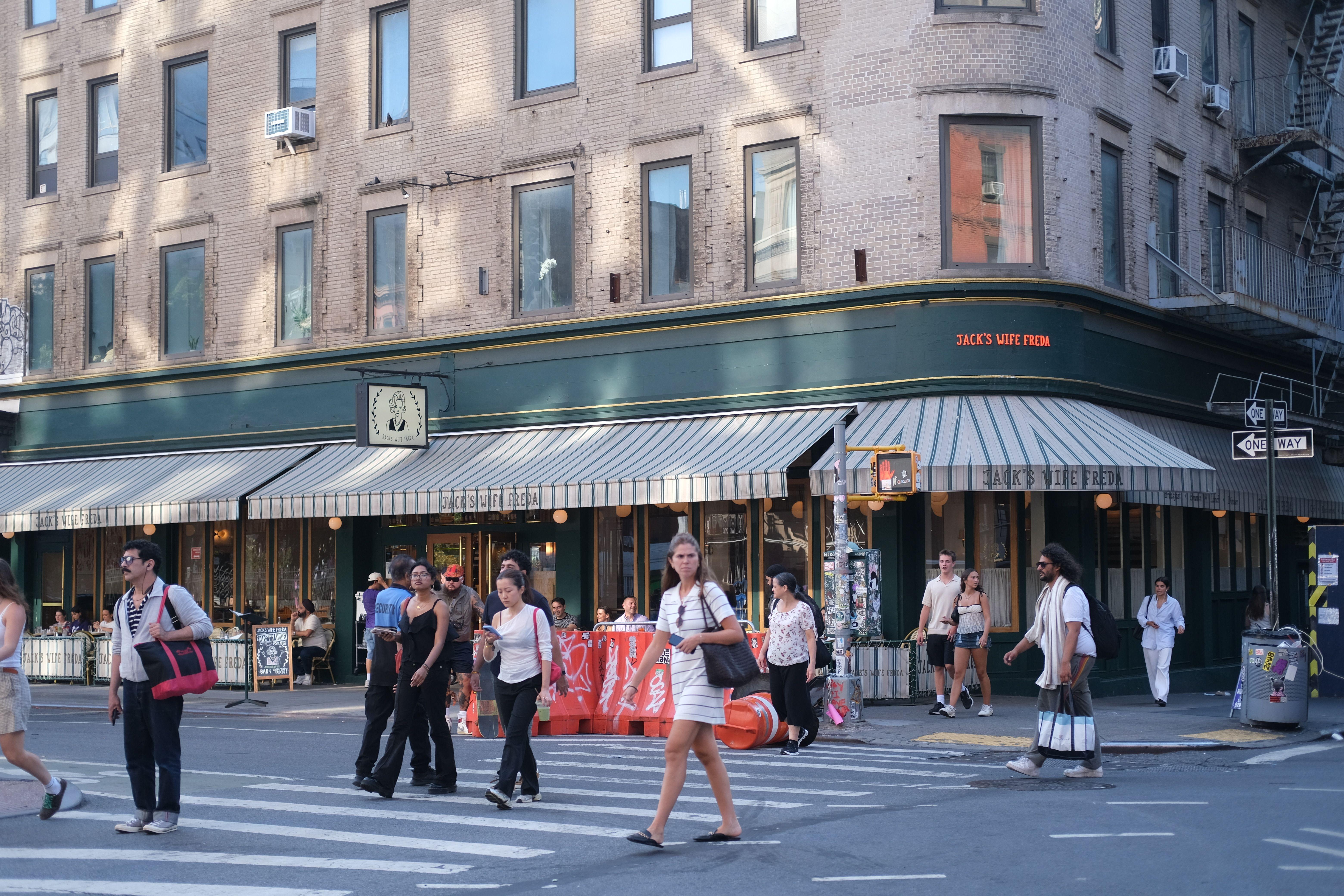 People crossing the street near Jack's Wife Freda cafe on a sunny day.