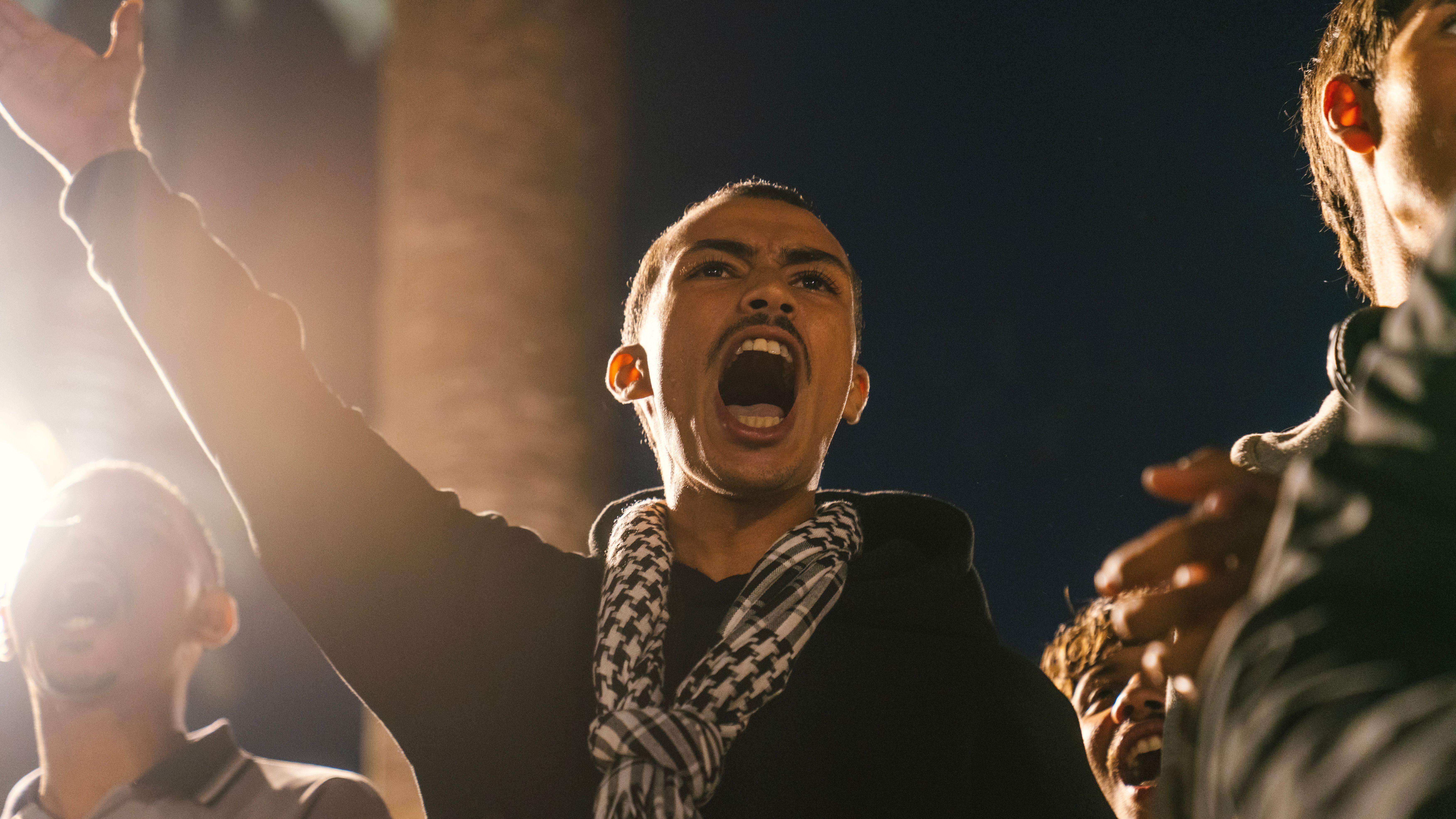 A young protestor passionately shouting during a nighttime rally in Rabat, Morocco.