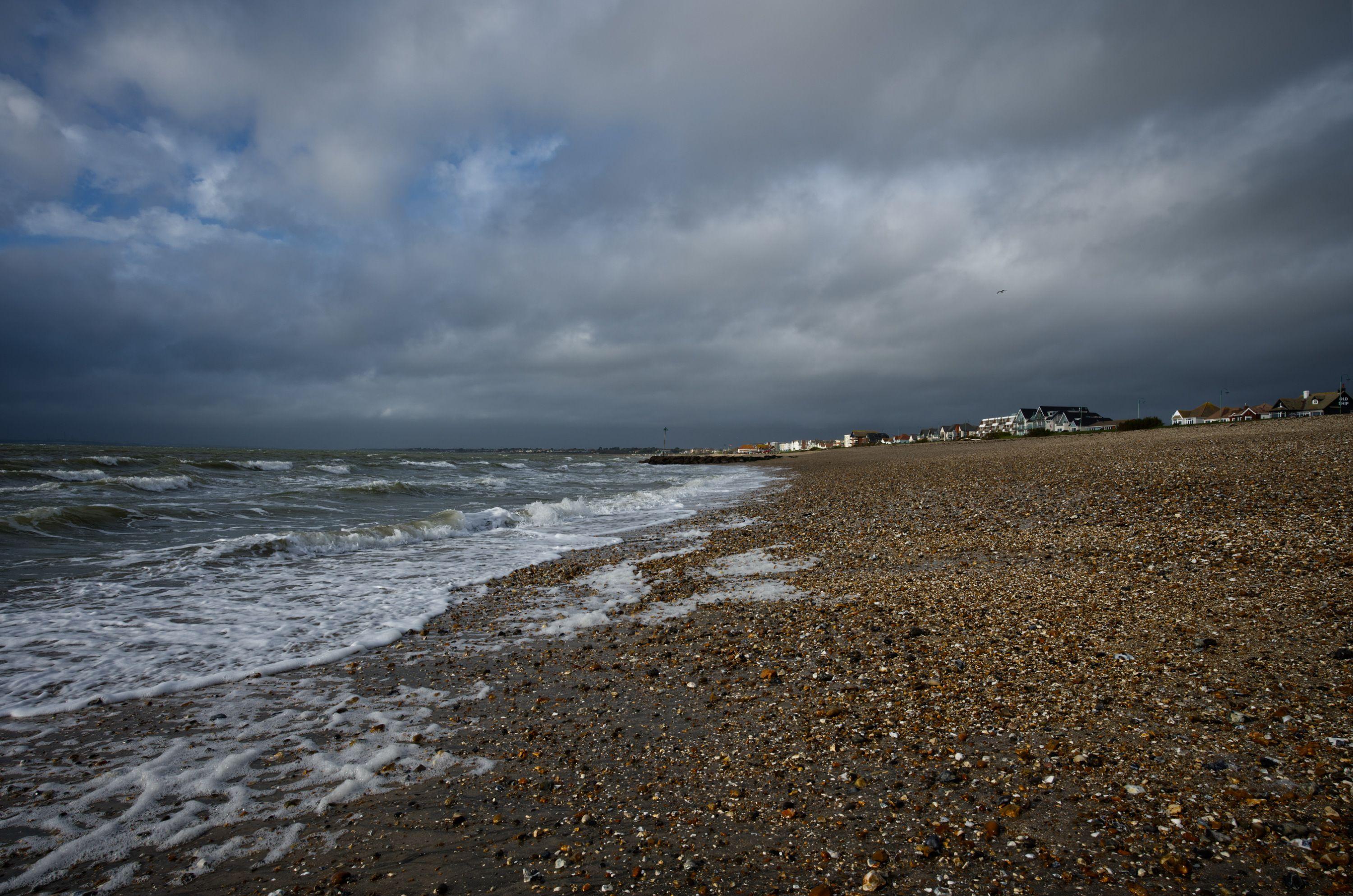 Moody beach scene at Lee-on-the-Solent, England, with stormy skies and waves crashing ashore.