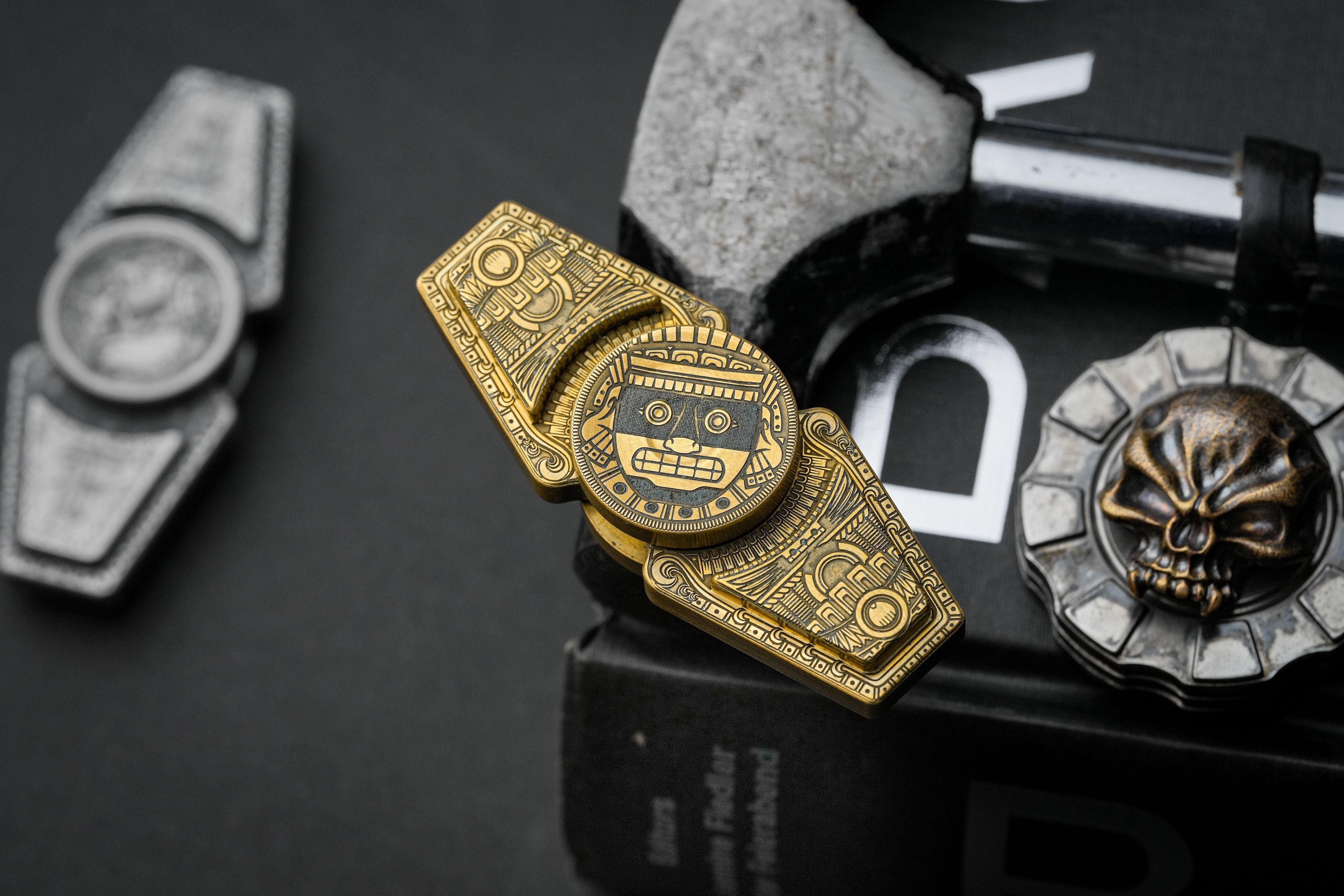Aztec-themed metallic fidget toy with intricate designs on a dark background, perfect for cultural interest and stress relief.
