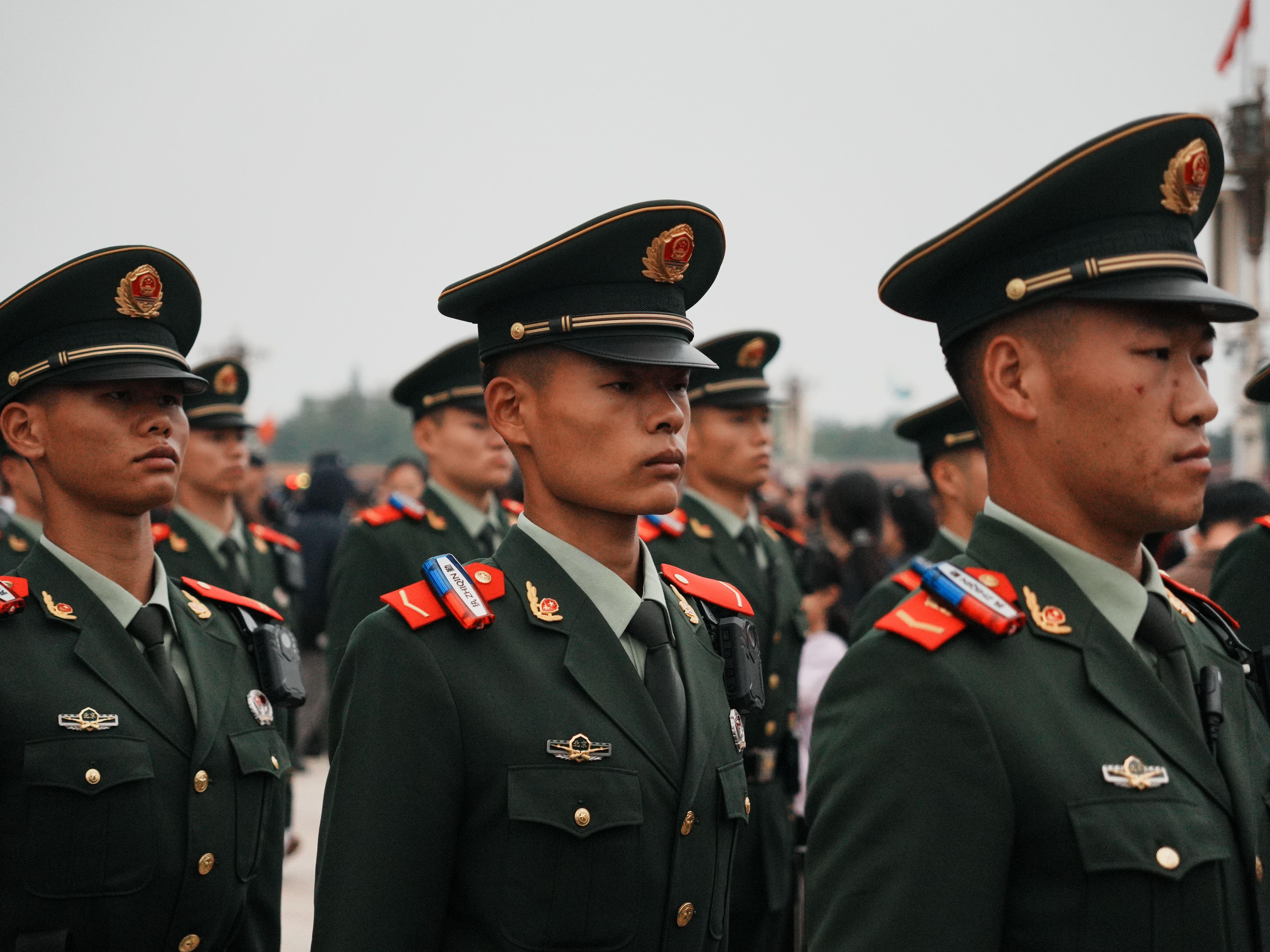 Close-up of military personnel in green uniforms and hats during a parade.