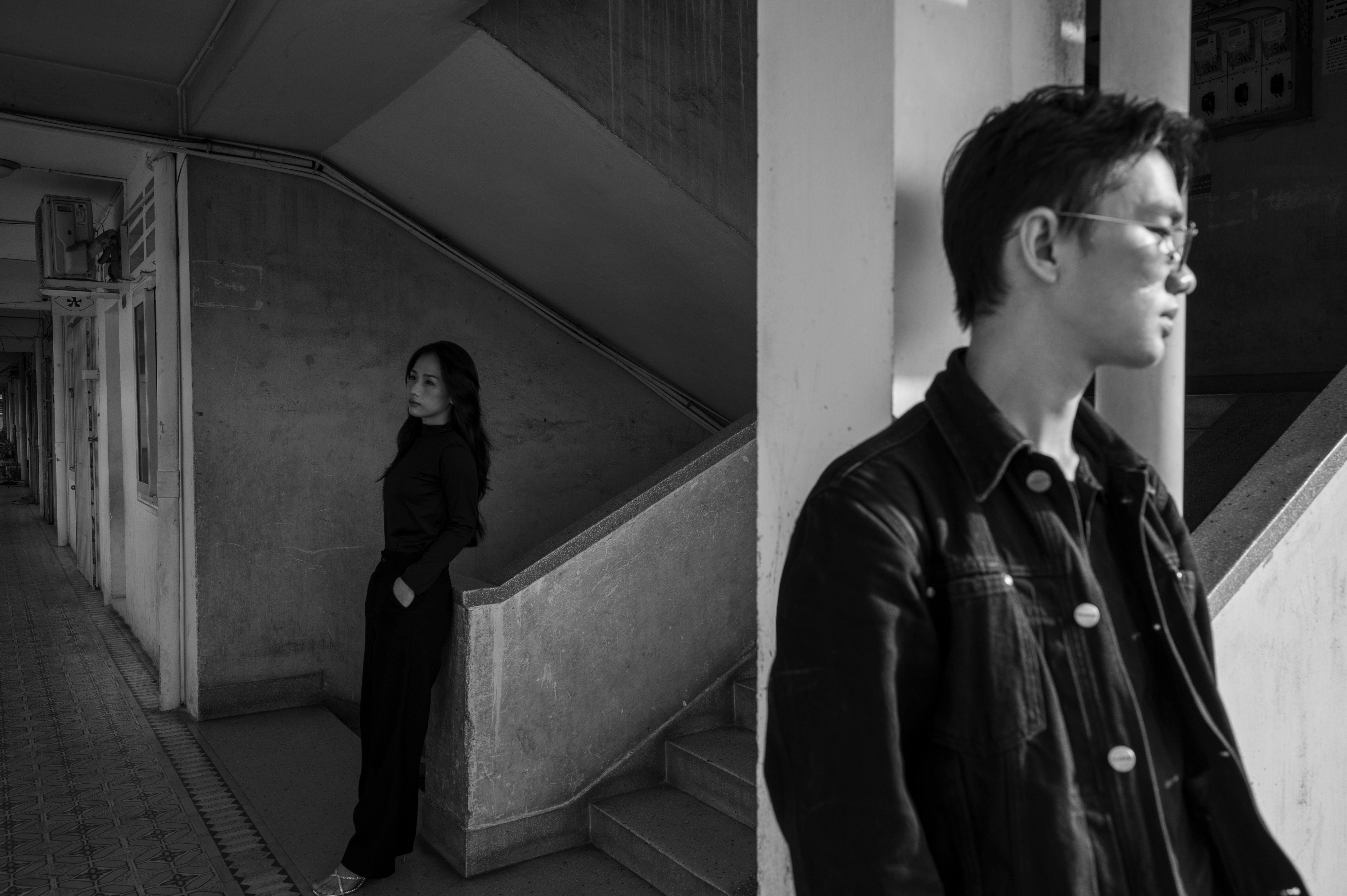 Monochrome portrait of two adults in an urban setting, creating a dramatic mood.