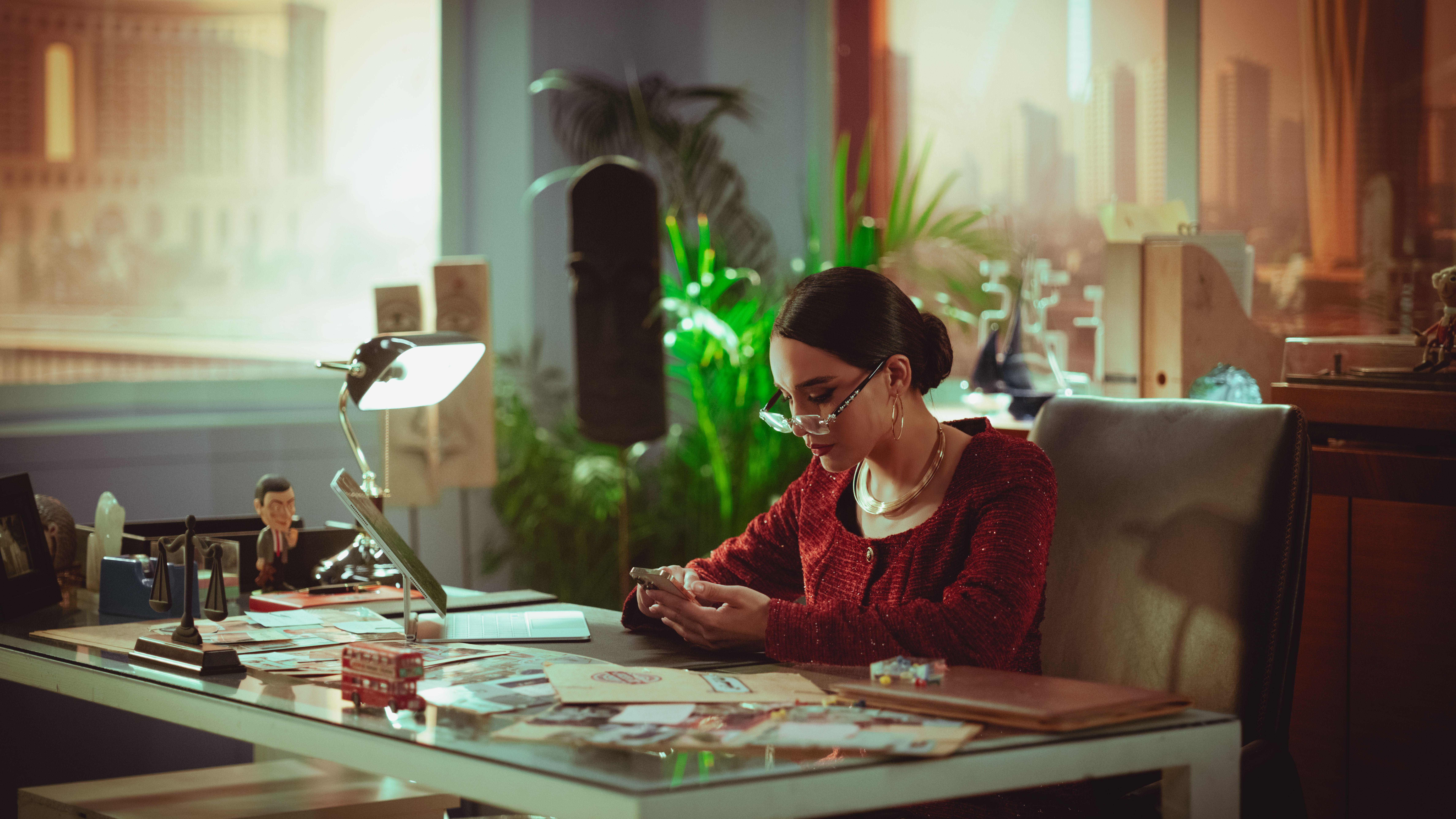 Woman using smartphone in a modern office with cityscape background, Baghdad, Iraq.