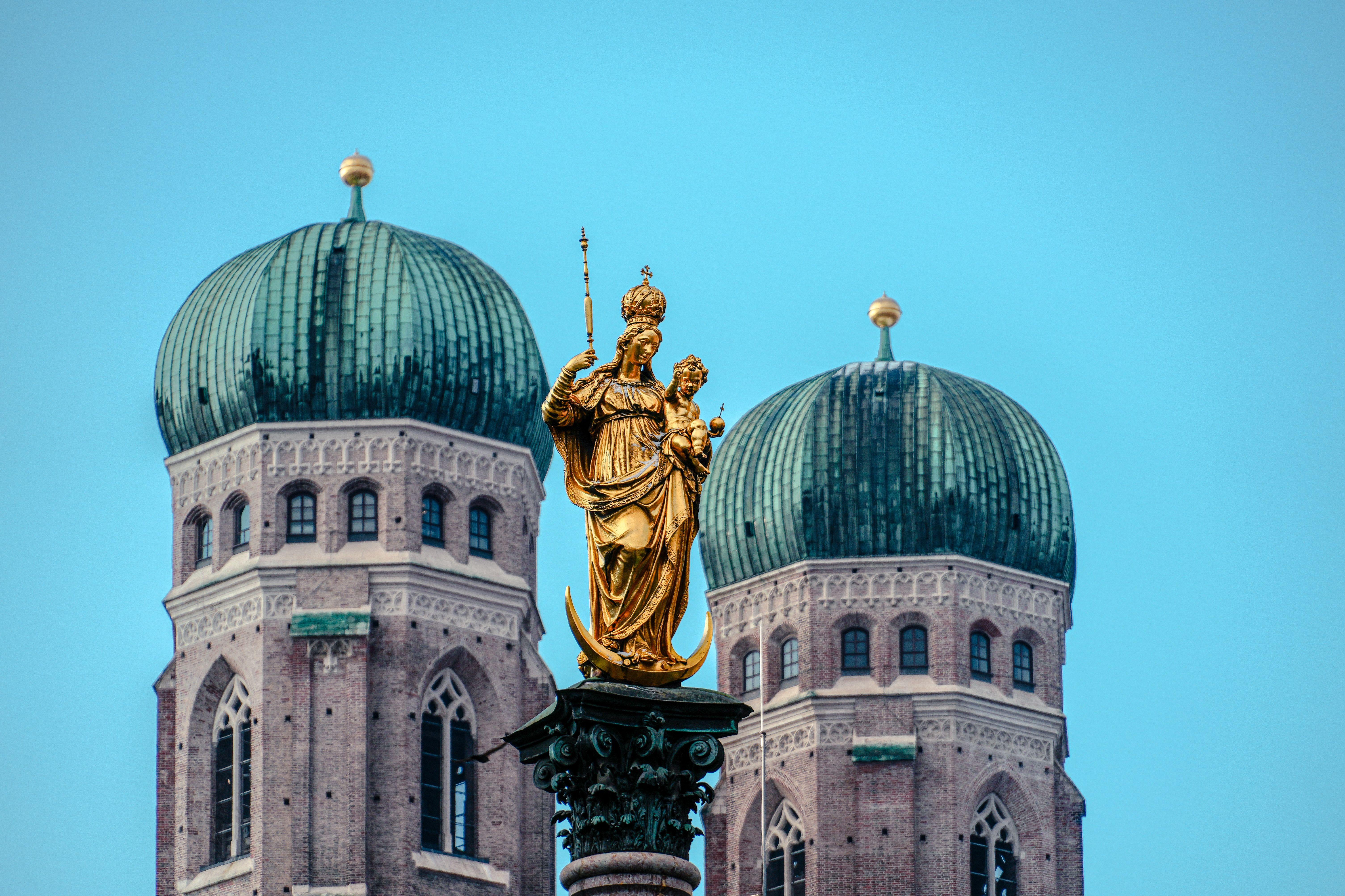 Golden statue of Mary at Marienplatz with Frauenkirche towers in Munich, Germany.