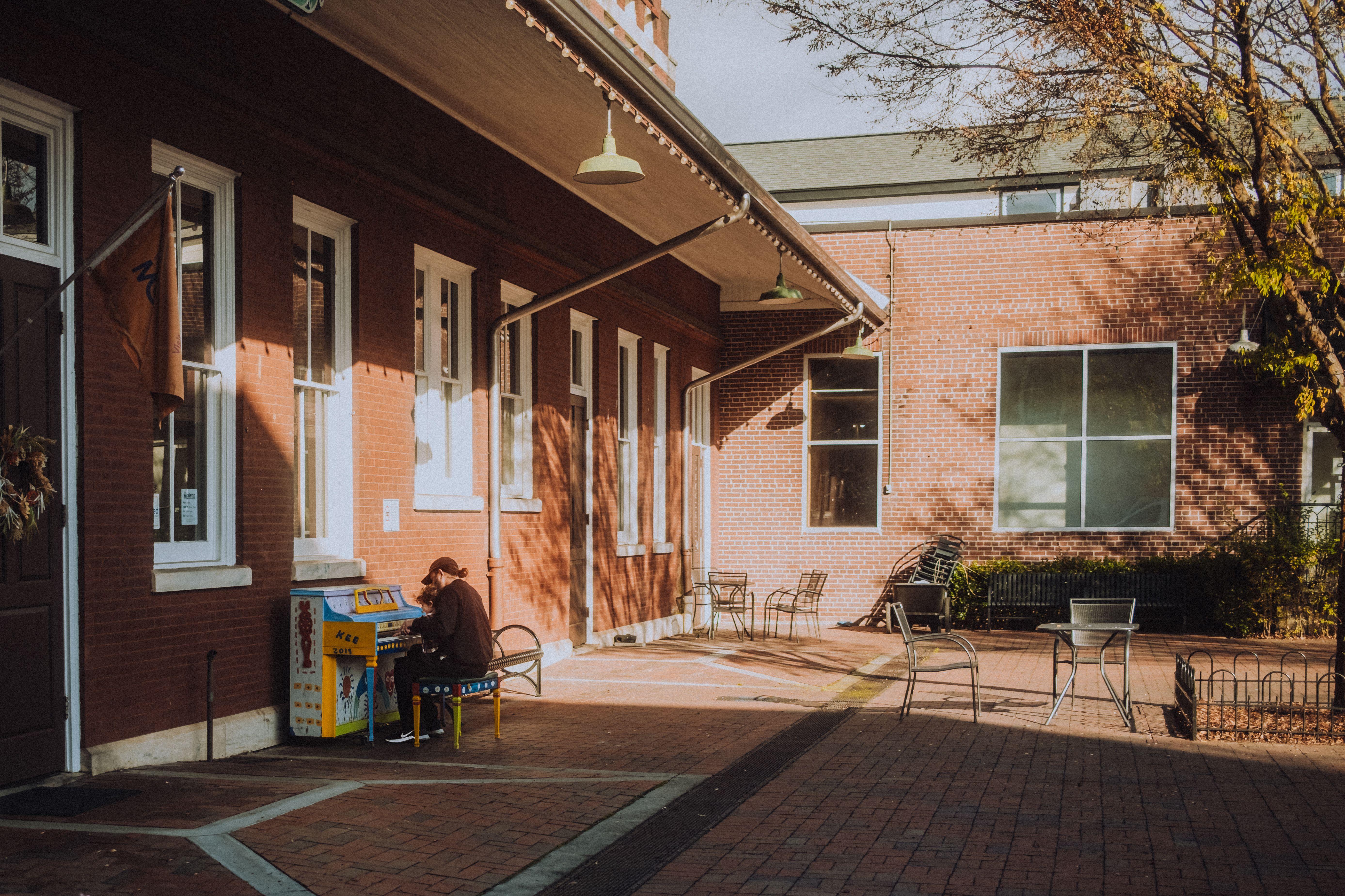 A tranquil courtyard scene with a street piano player, surrounded by charming brick buildings.