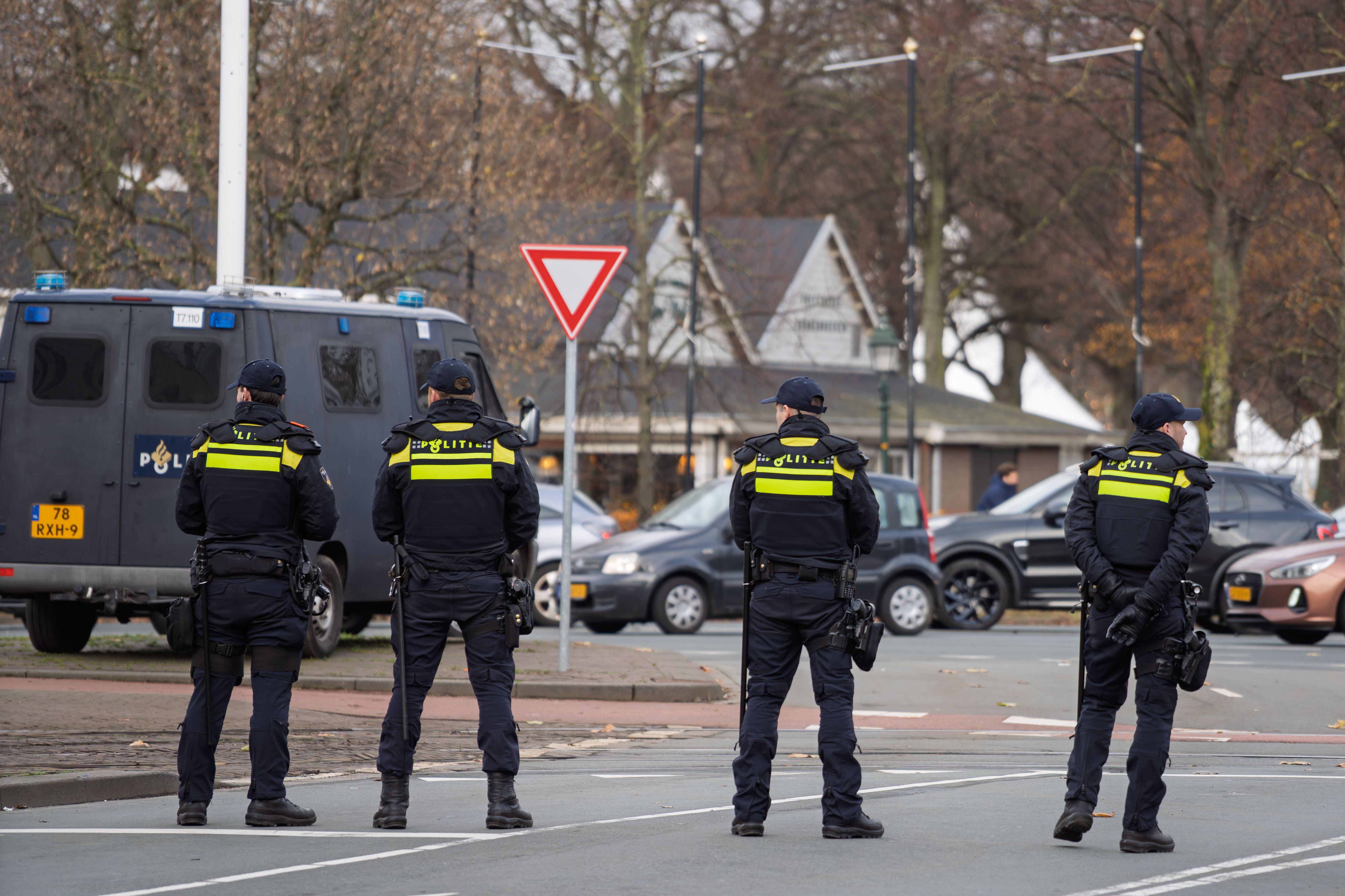 Four police officers stand vigilant on city street near patrol van, ensuring public safety.