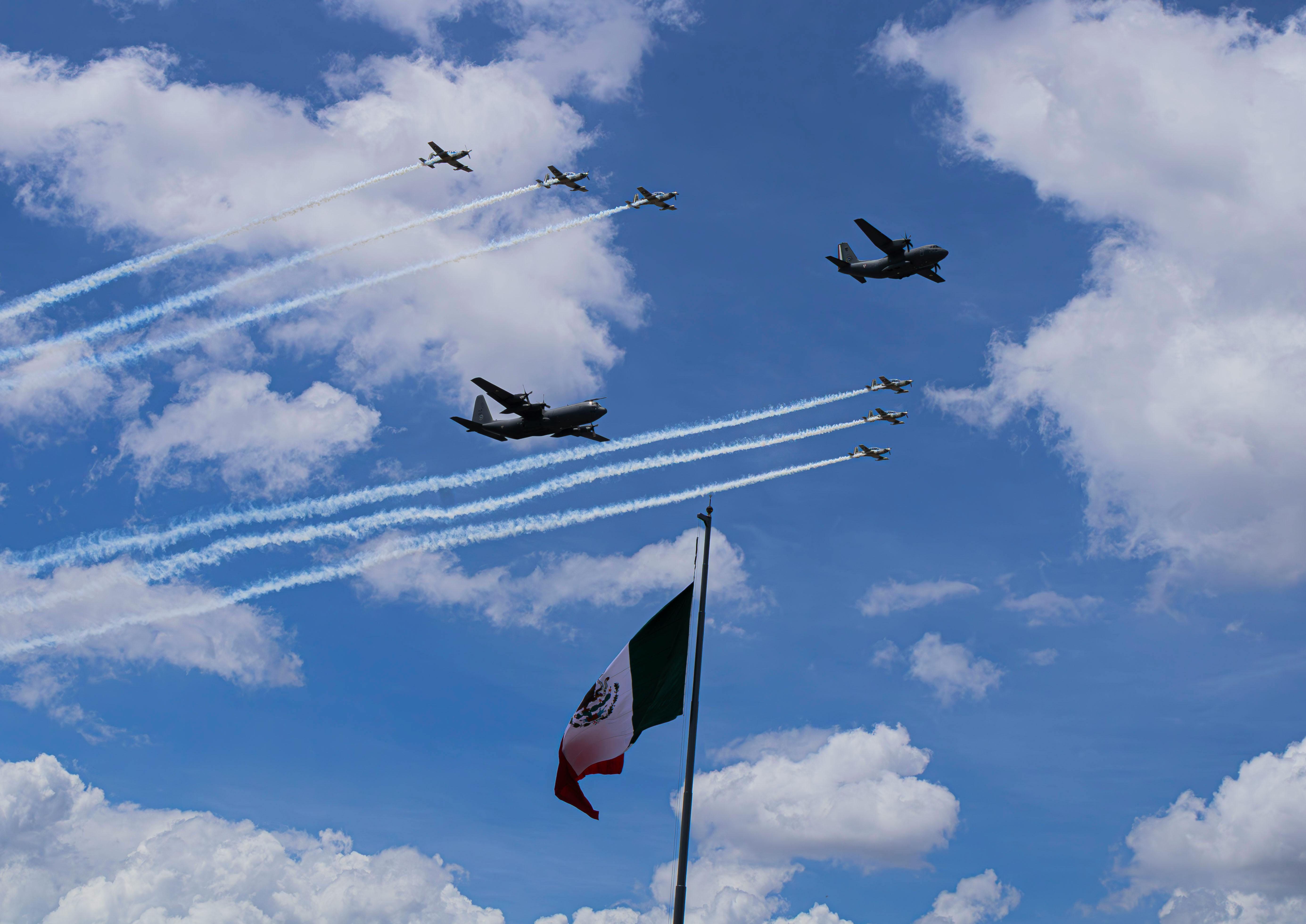 Dynamic military airshow with jets and smoke trails above a Mexican flag.