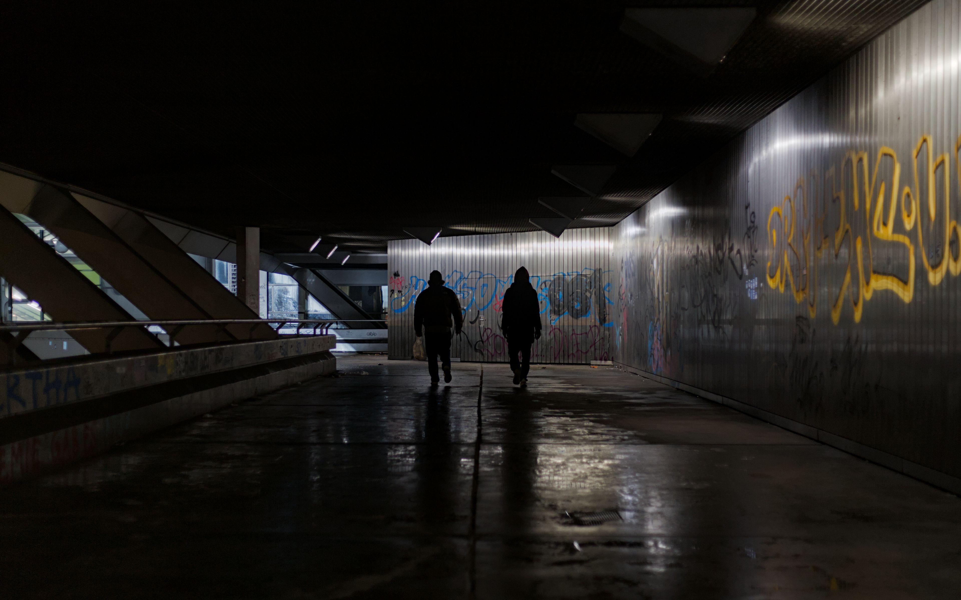 Dramatic nighttime shot of people walking through a graffiti-covered tunnel in Berlin's ICC area.