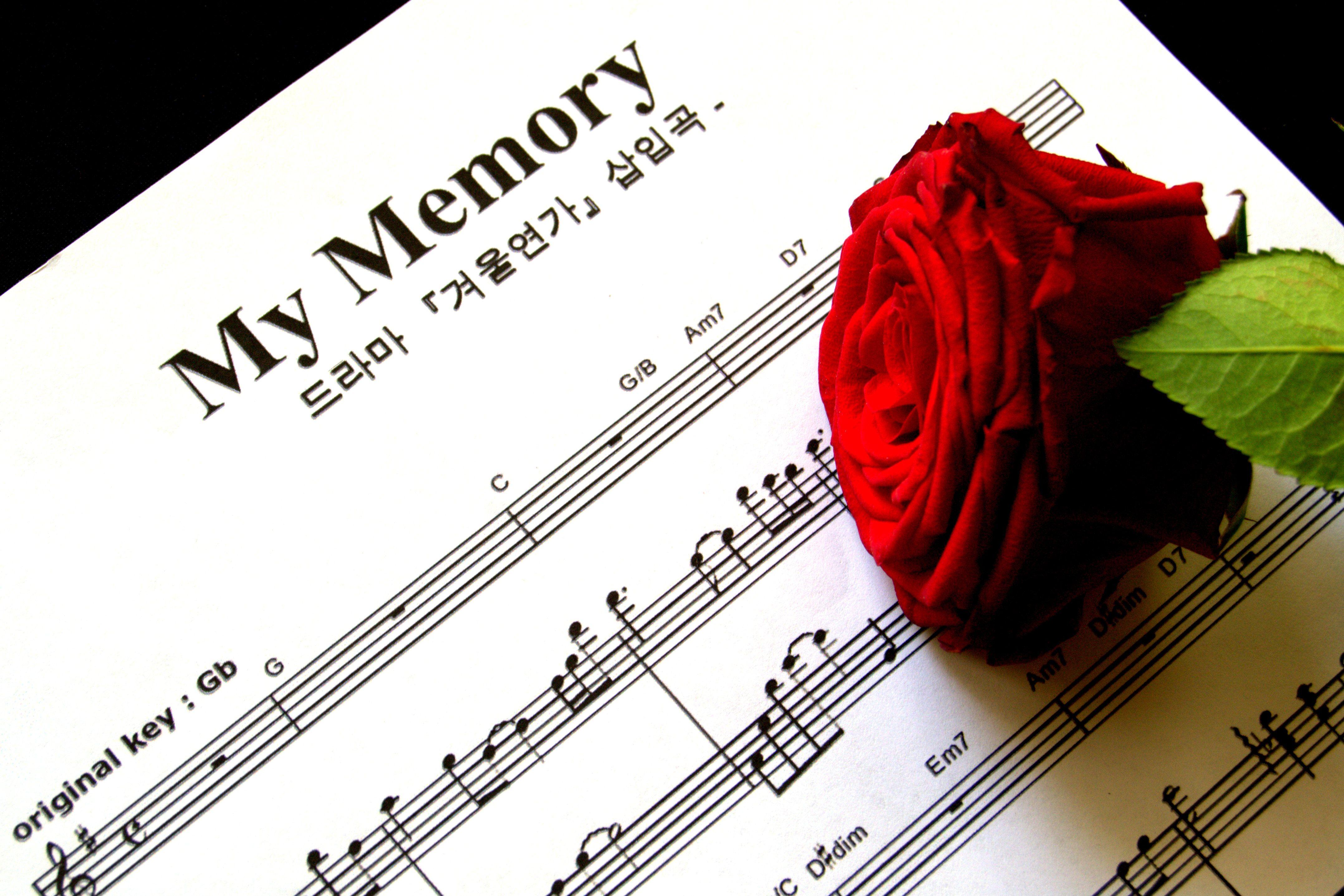 A red rose rests on sheet music titled 'My Memory', evoking romance and nostalgia.