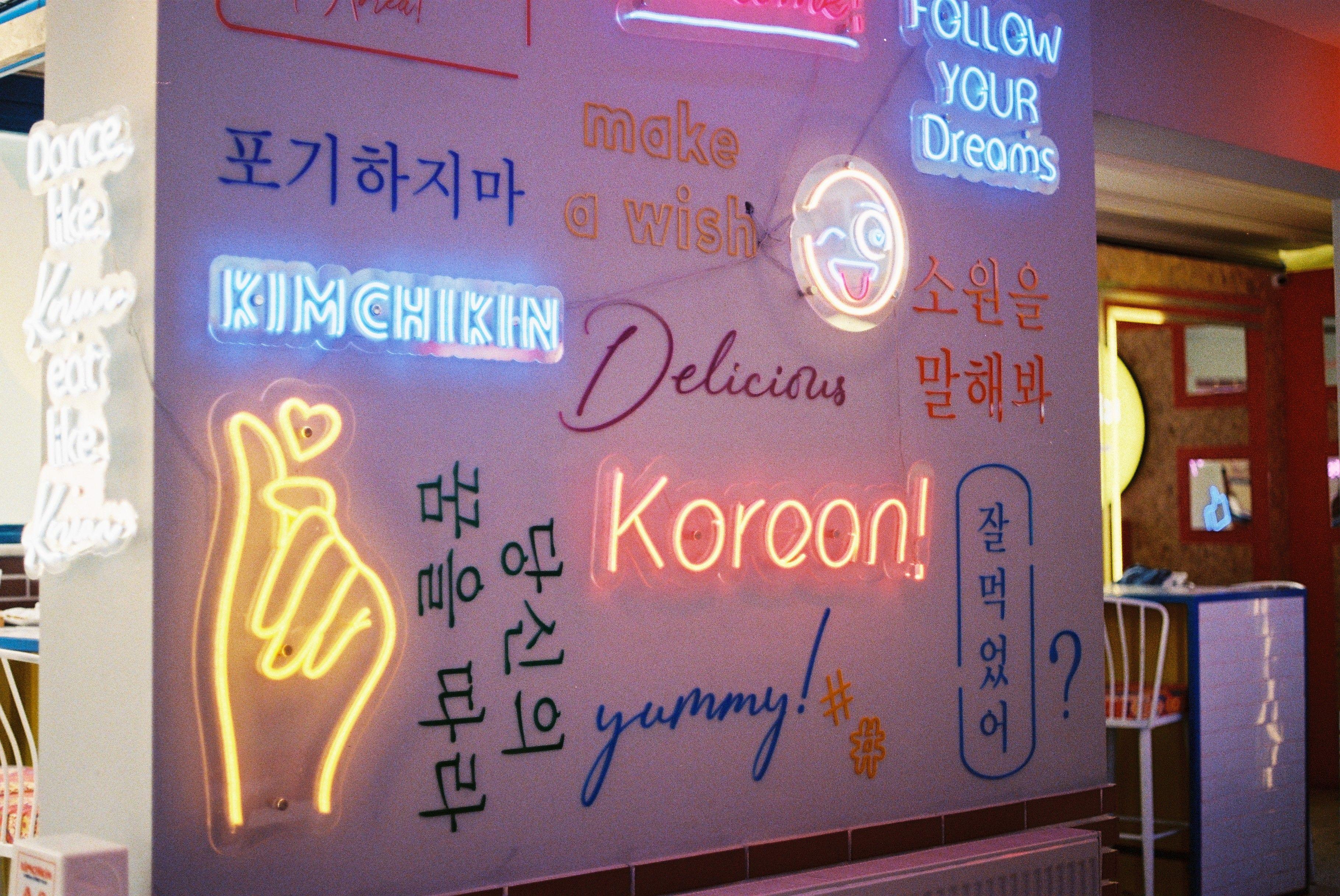 Vibrant neon signage in a café, showcasing Korean and English phrases.