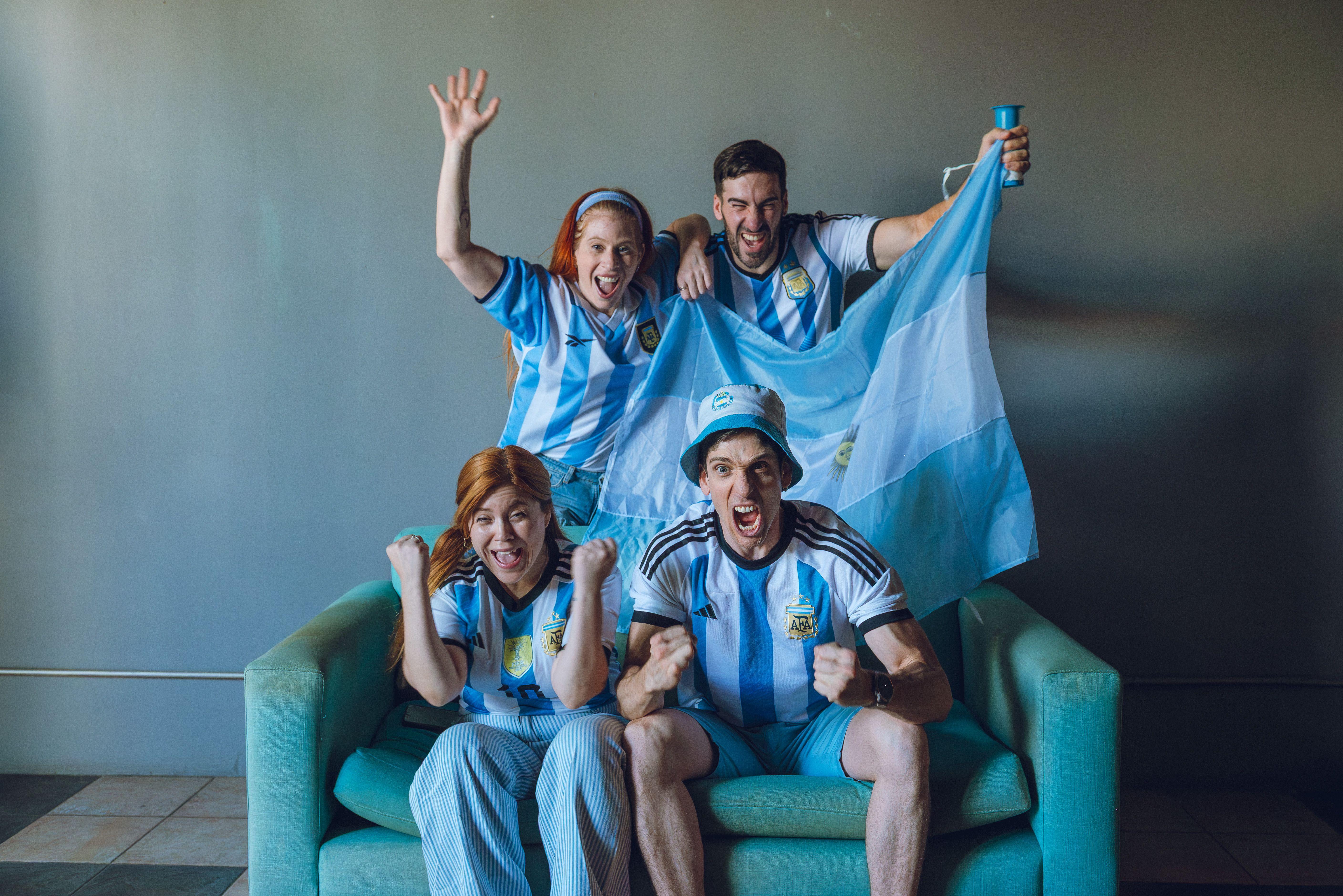 Group of fans celebrating Argentina's soccer victory at home, wearing team jerseys.