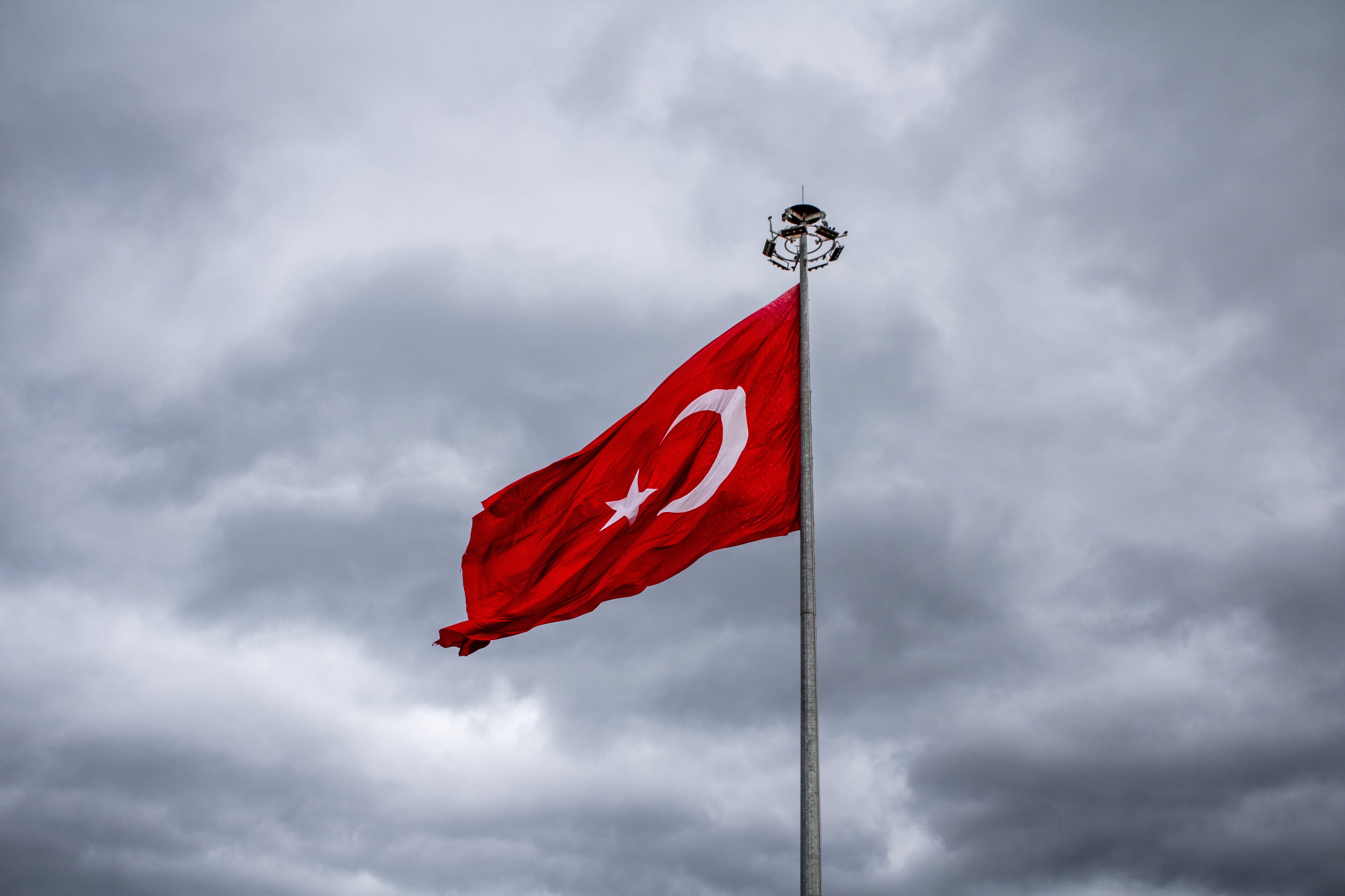 Turkish national flag waving against a backdrop of dramatic gray clouds, symbolizing national pride.