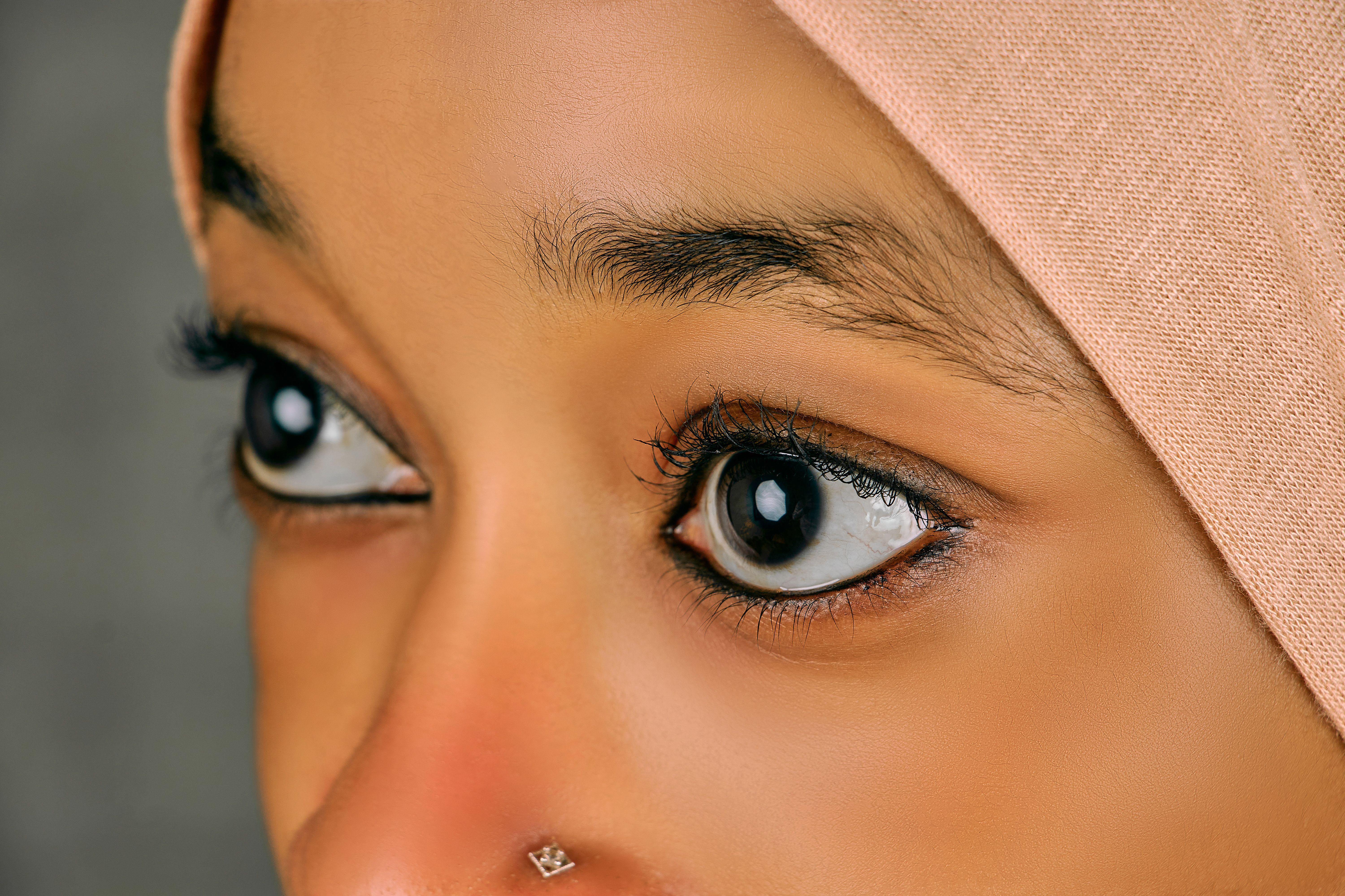 Detailed close-up of a woman's eyes wearing a hijab and nose ring, showcasing beauty.