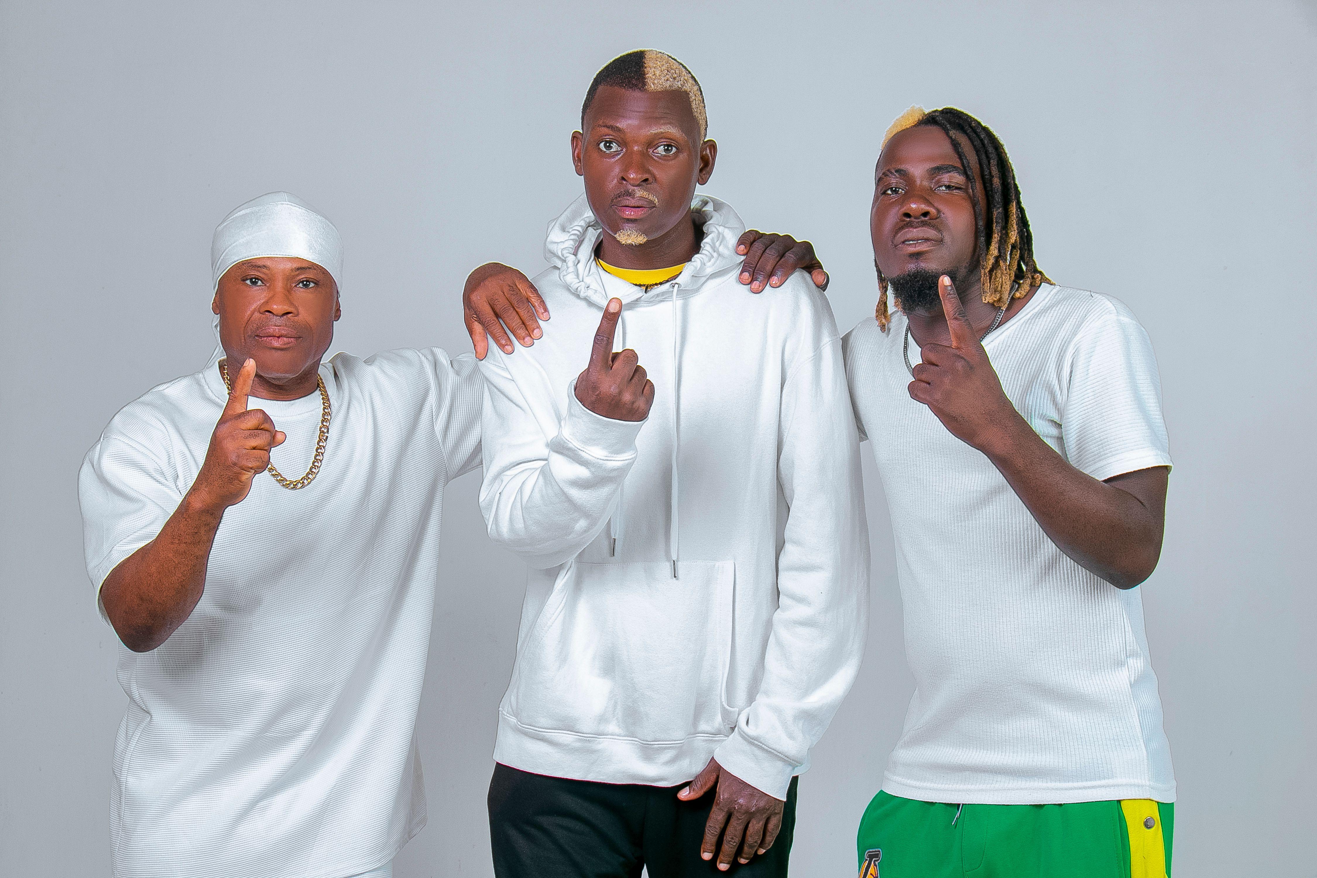 Three men in casual white clothing expressing unity and confidence on a neutral background.