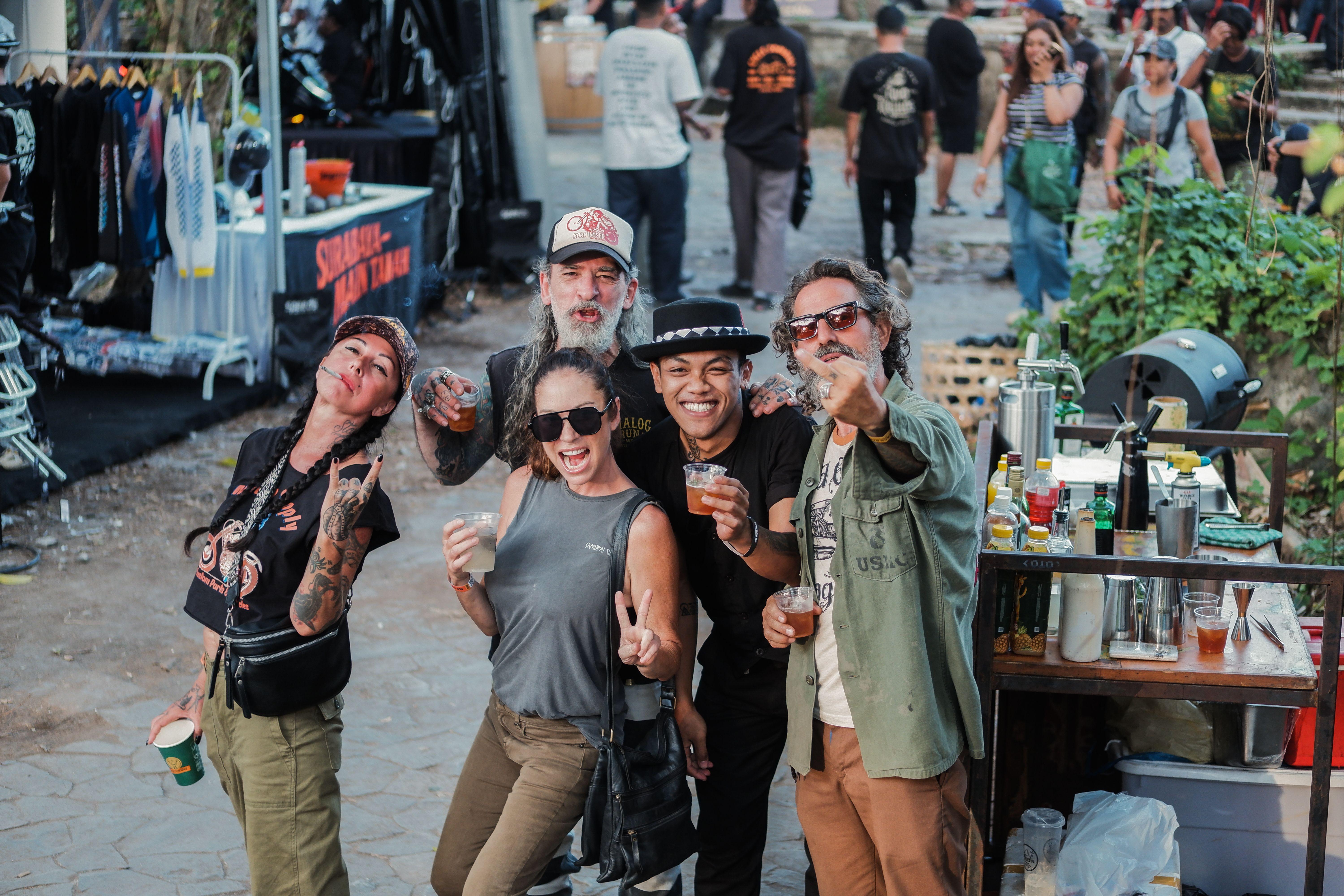Group of friends enjoying an outdoor event with drinks and laughter, surrounded by vendors.