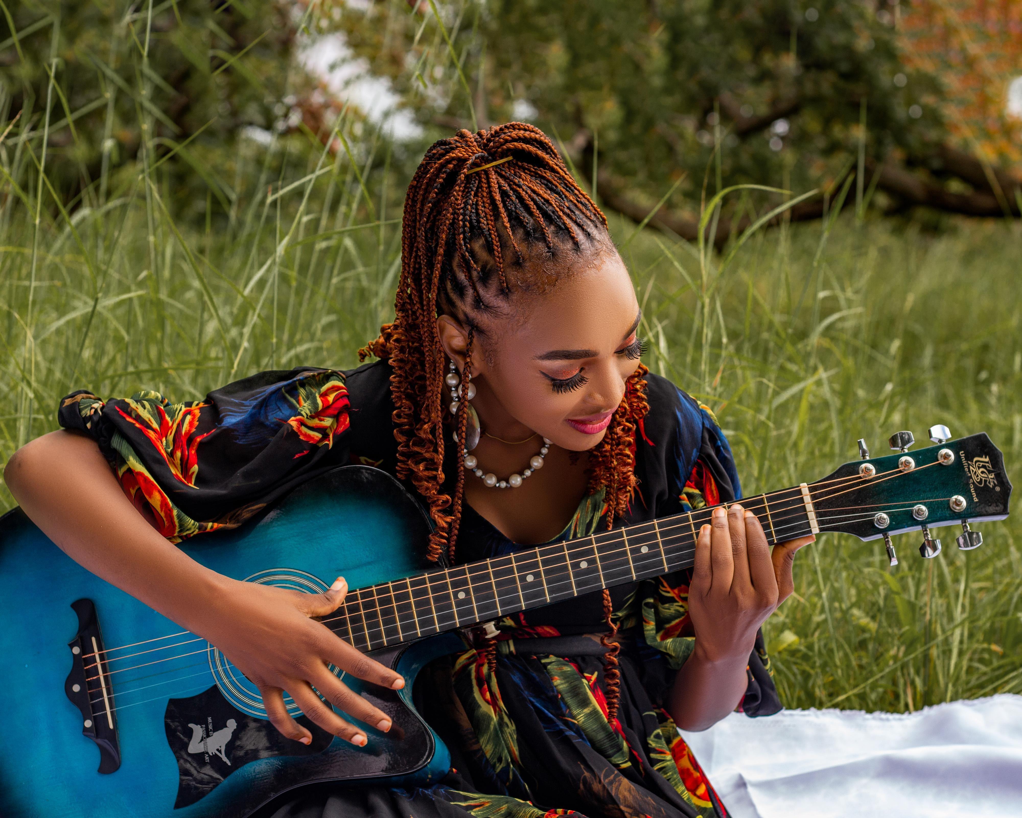 A woman enjoying playing guitar in a sunlit meadow, evoking a sense of peace and creativity.