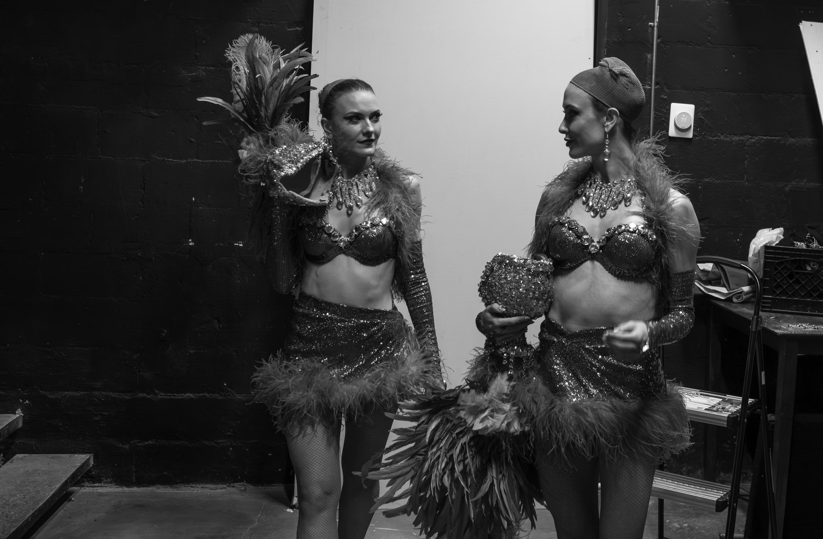 Black and white image of two cabaret dancers in sparkling costumes backstage.